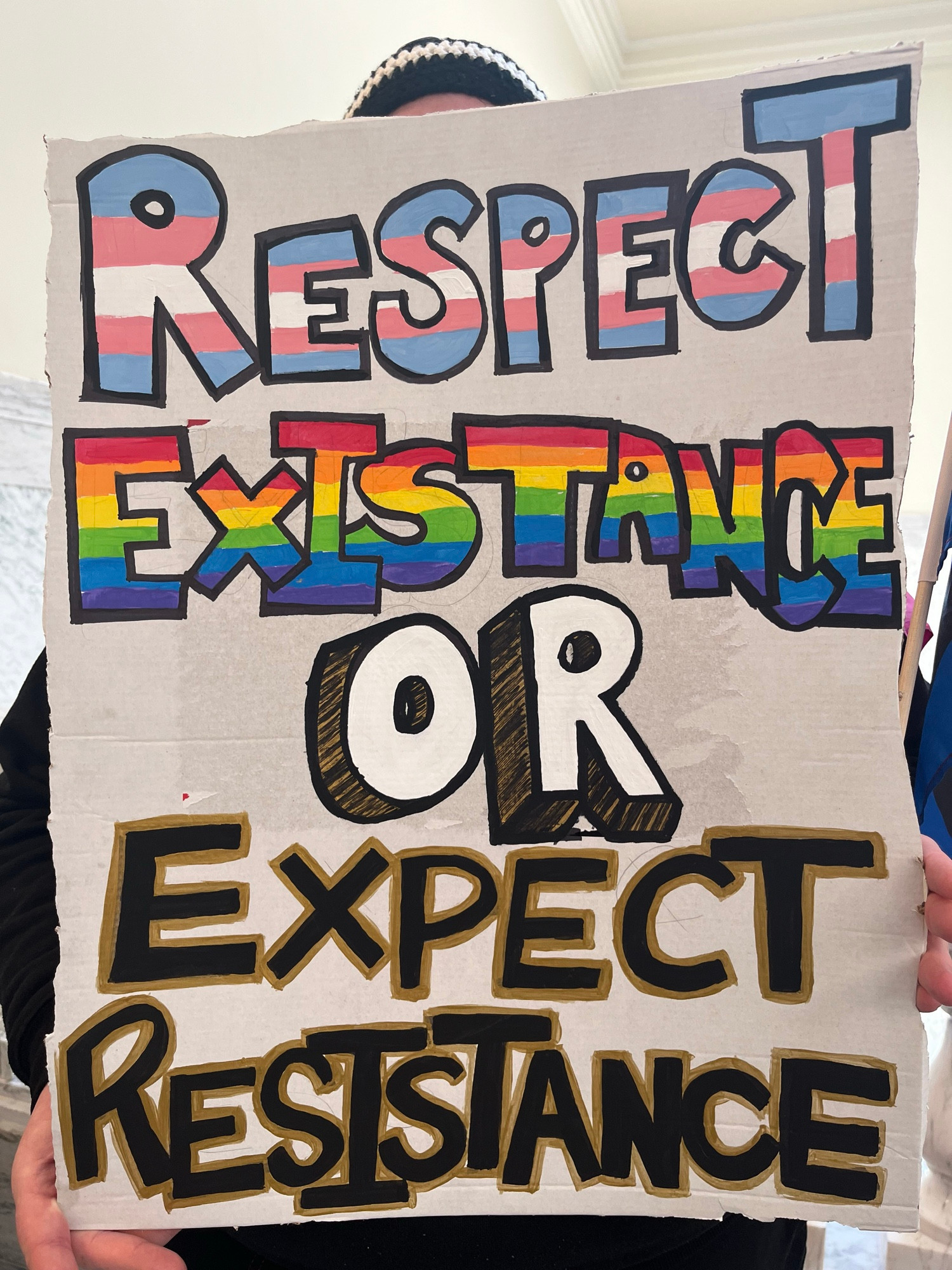 A demonstrator holds a sign stating Respect Existence or Expect Resistance.