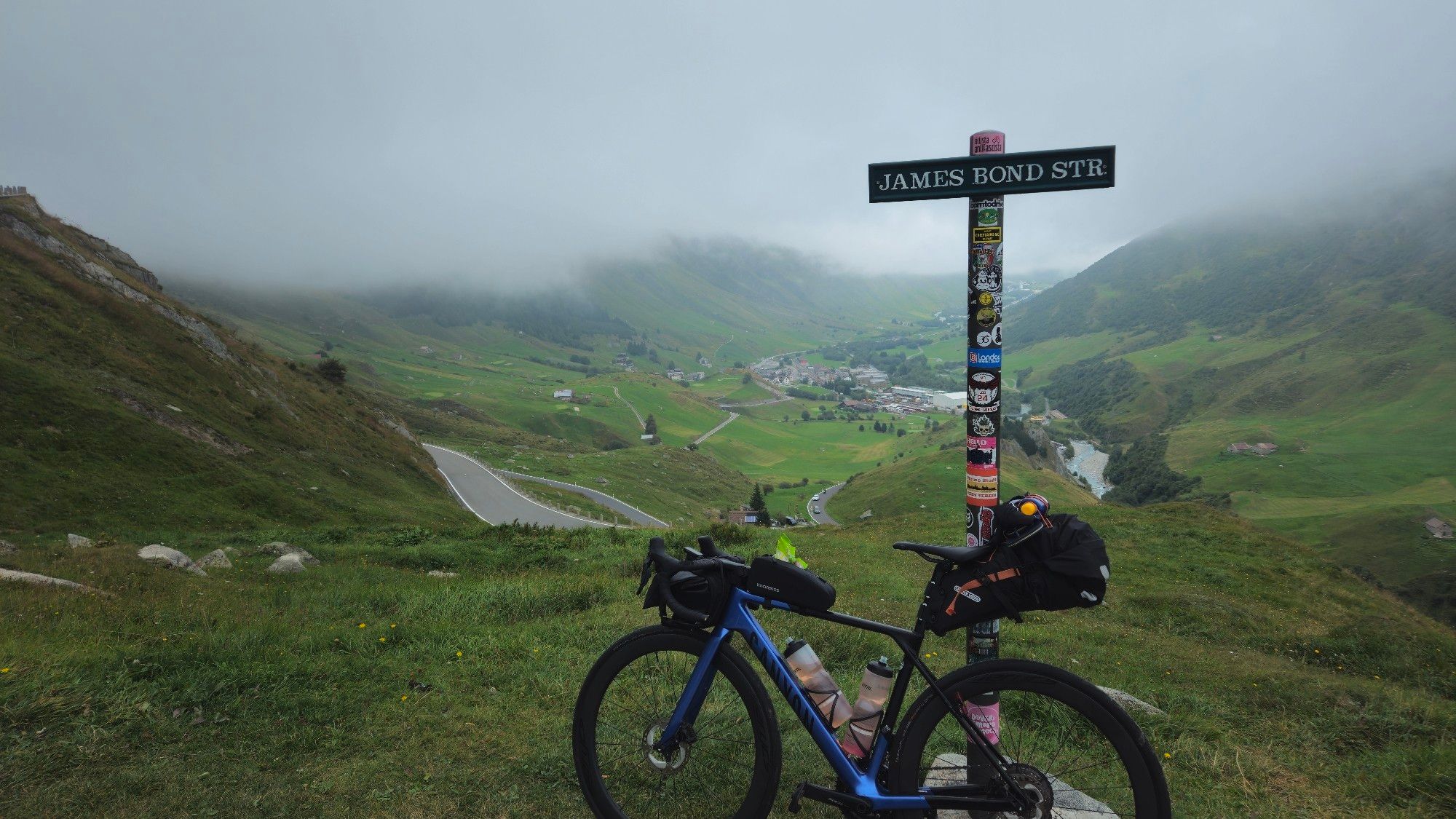 Berpacktes Rennrad am Schild James Bond Straße mit Block ins Tal von Furkapass, wo James Bond gedreht wurde