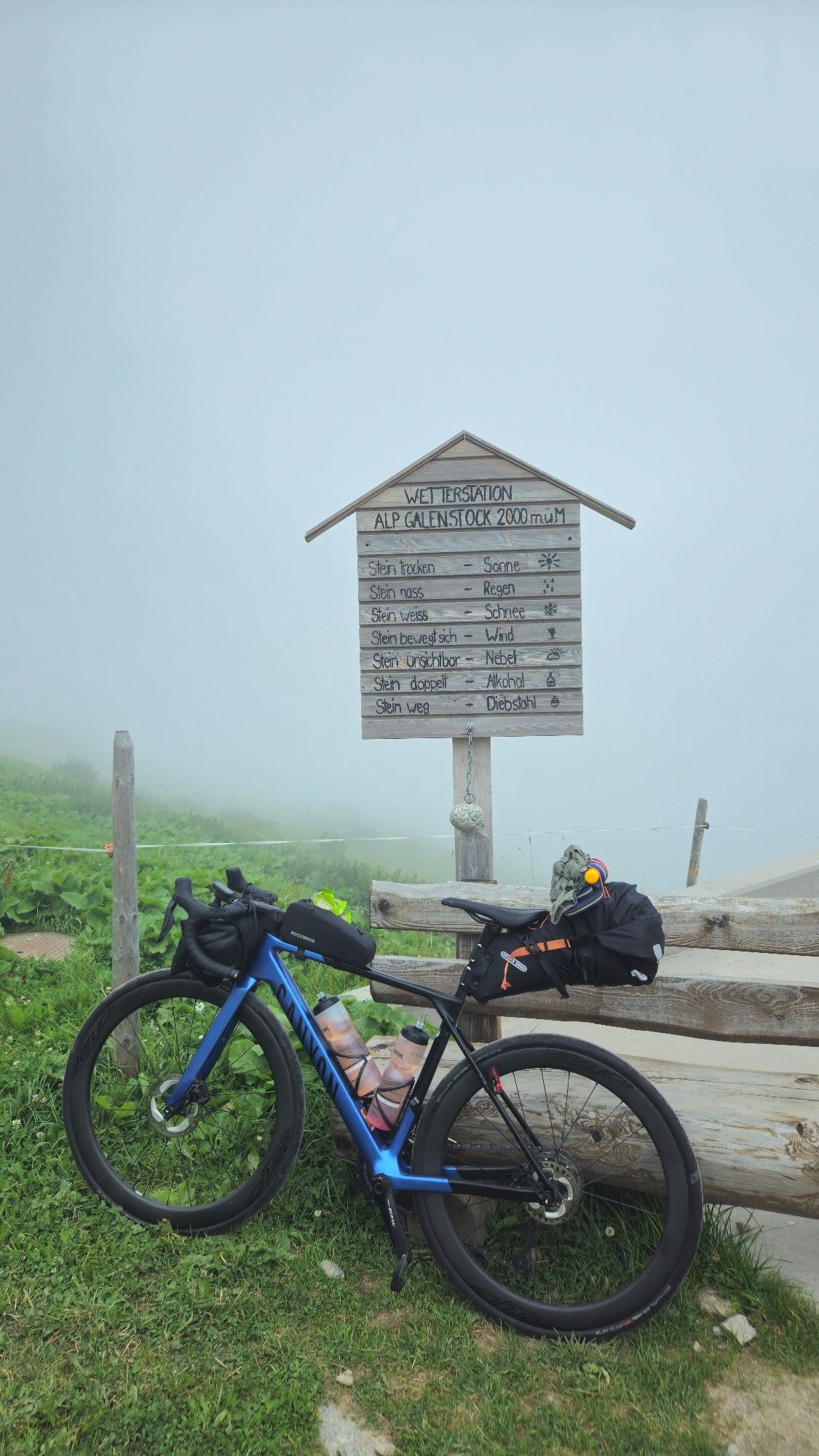 Rennrad lehnt vor Wetterstein -Schild. Dahinter ist alles weiß von Wolken und Nebel, kaum Sicht