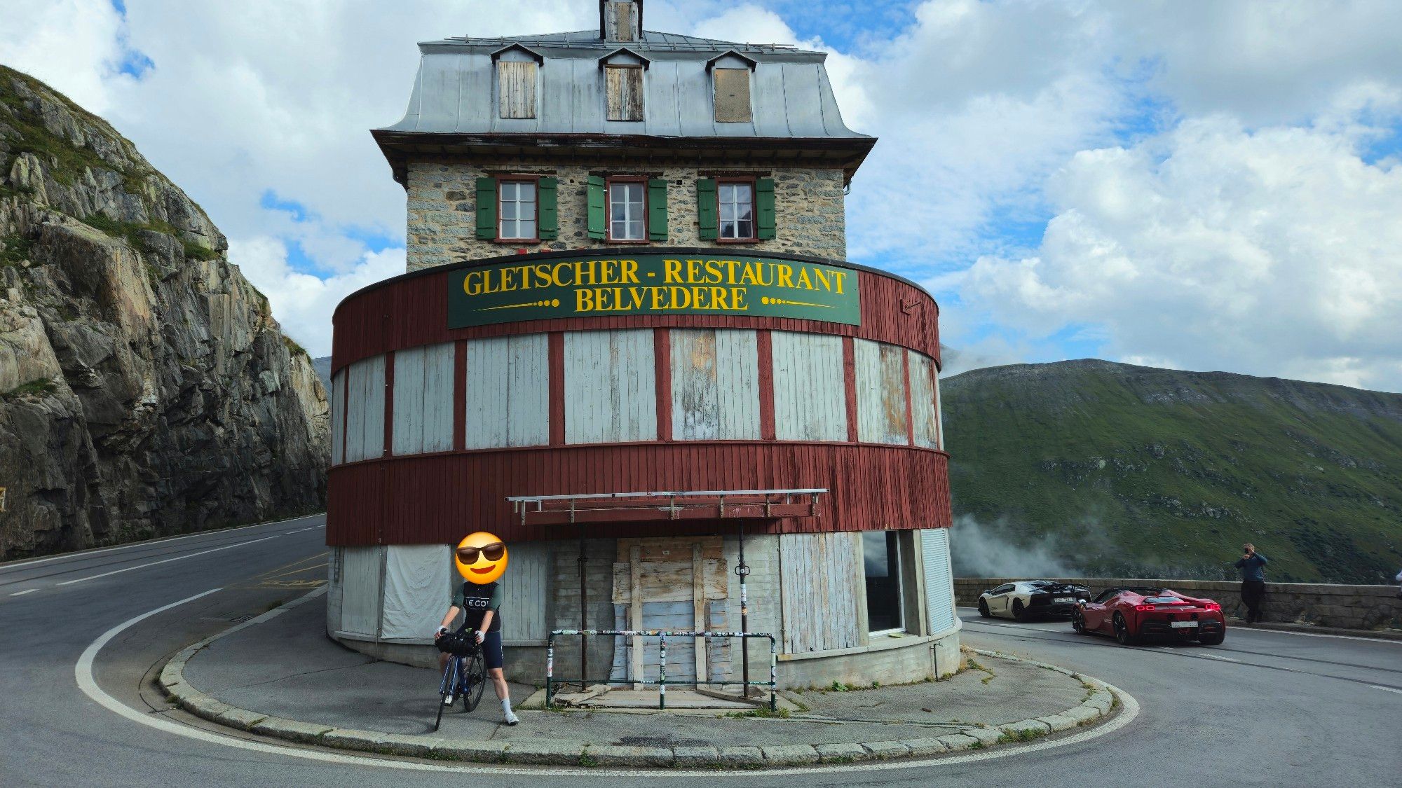 Rennradfahrer steht vor dem Gletscher Restaurant Belvedere rechts fahren noch zwei Lamborghini um die Kurve