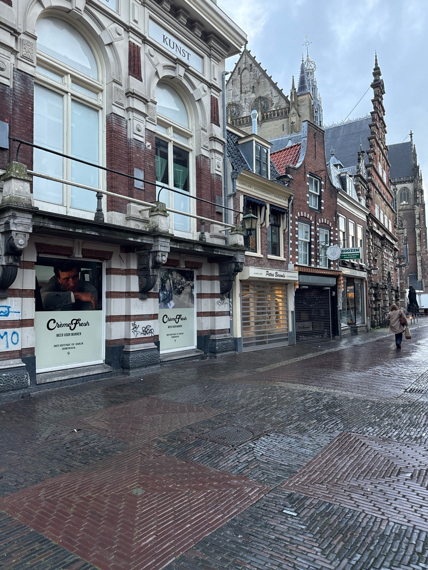 A few of wet and patterned cobblestone streets above which rise the fronts of 18th and 17th century buildings in the background, you can see a tiny bit of the big church in the center of town. Mozart played its organ.