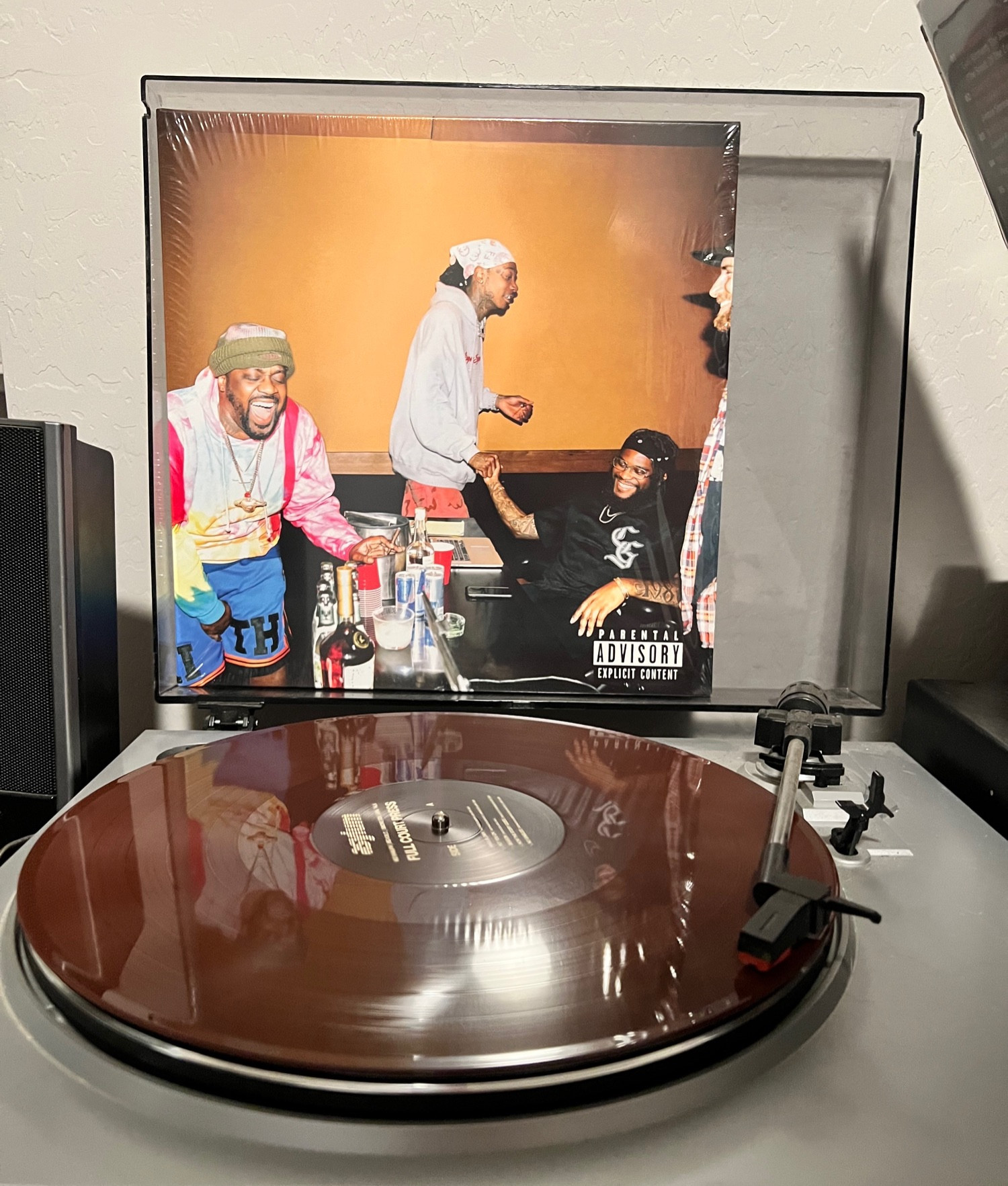 Chocolate color vinyl spinning on a turntable with a cover on display behind it. The album “Full Court Press” by wiz khalifa smoke dza and girl talk