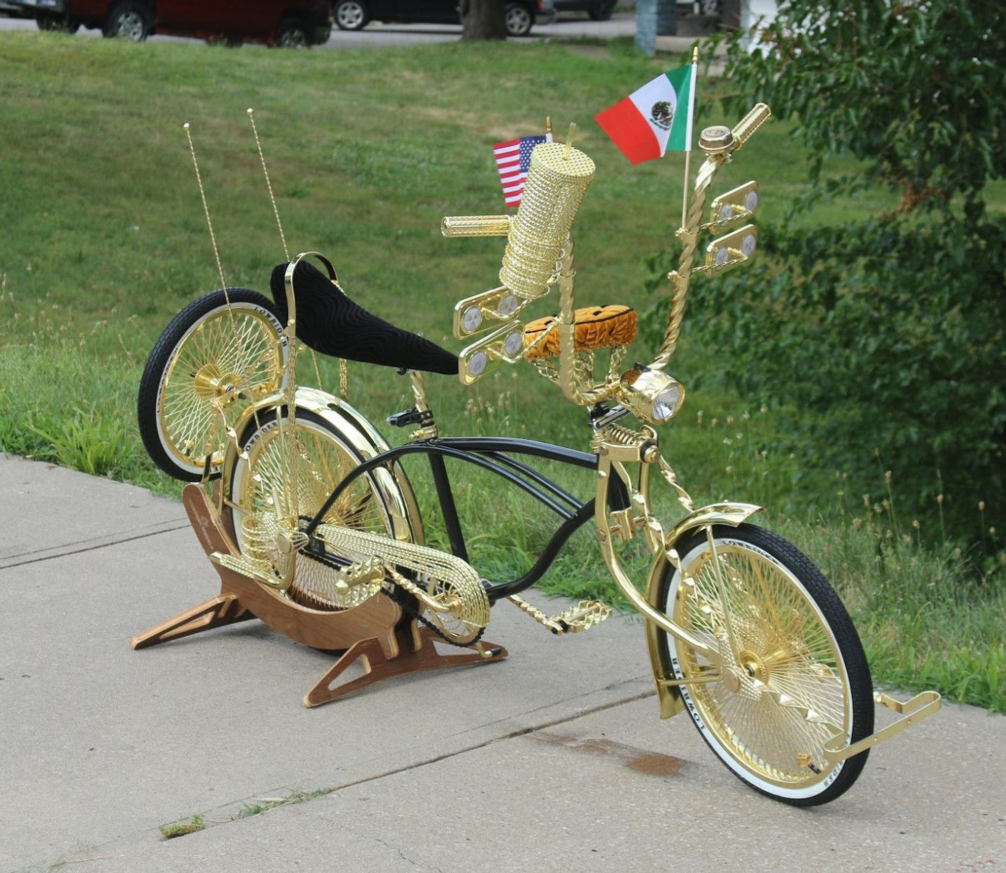 a tricked out lowrider bike; intricately detailed with black frame and gold accents everywhere. the wheels are triple-gold, along with the fenders, bumpers, handlebars, chainguard, pedals, crank arms, and numerous accessories. it's a beautiful bike.