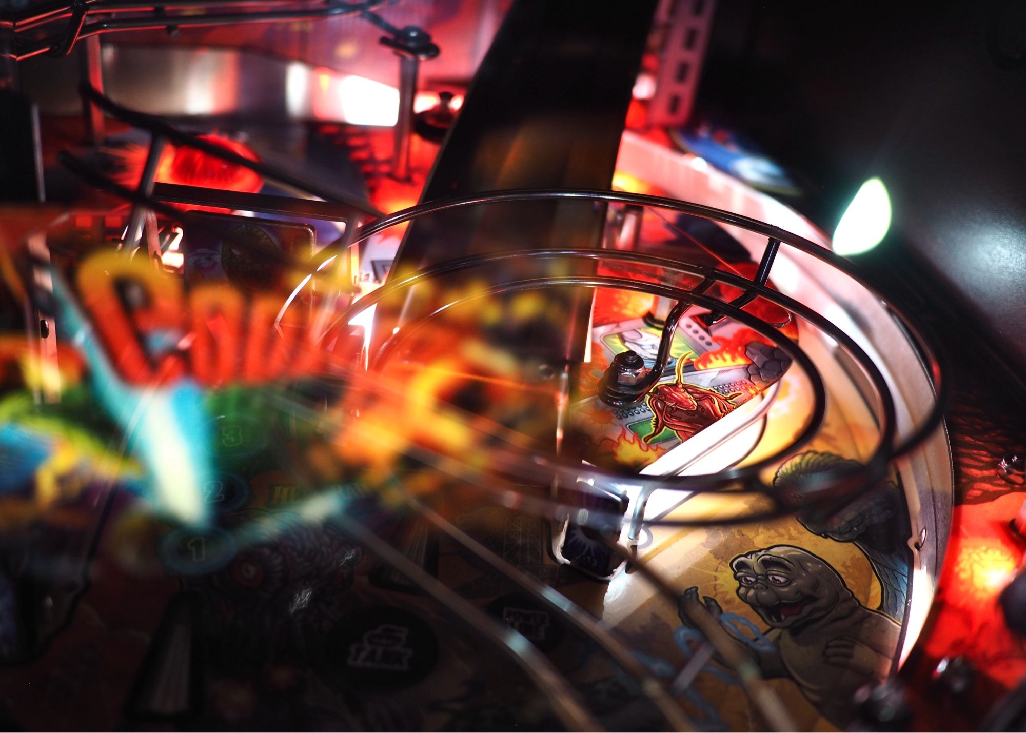 Dizzying reflections and moving parts inside a Jurassic Park pinball machine, composed as best I can