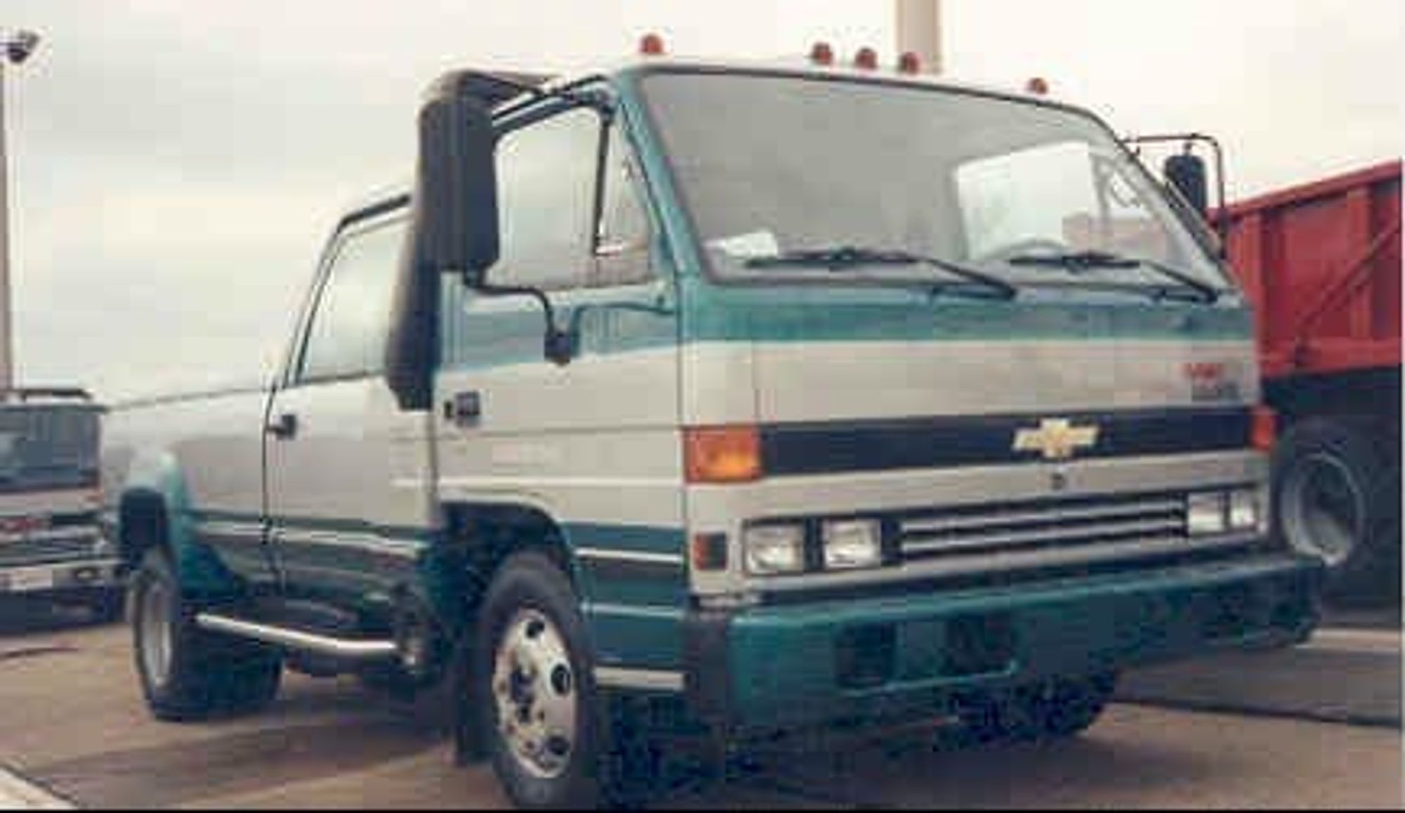 A teal and silver GMC/Chevy Lieutenant. The union of an Isuzu cab-over diesel and a CK-series crew cab. Should've been called the "Centaur". The now second-ugliest truck ever to grace American roads thanks to the existence of the Cybertruck.