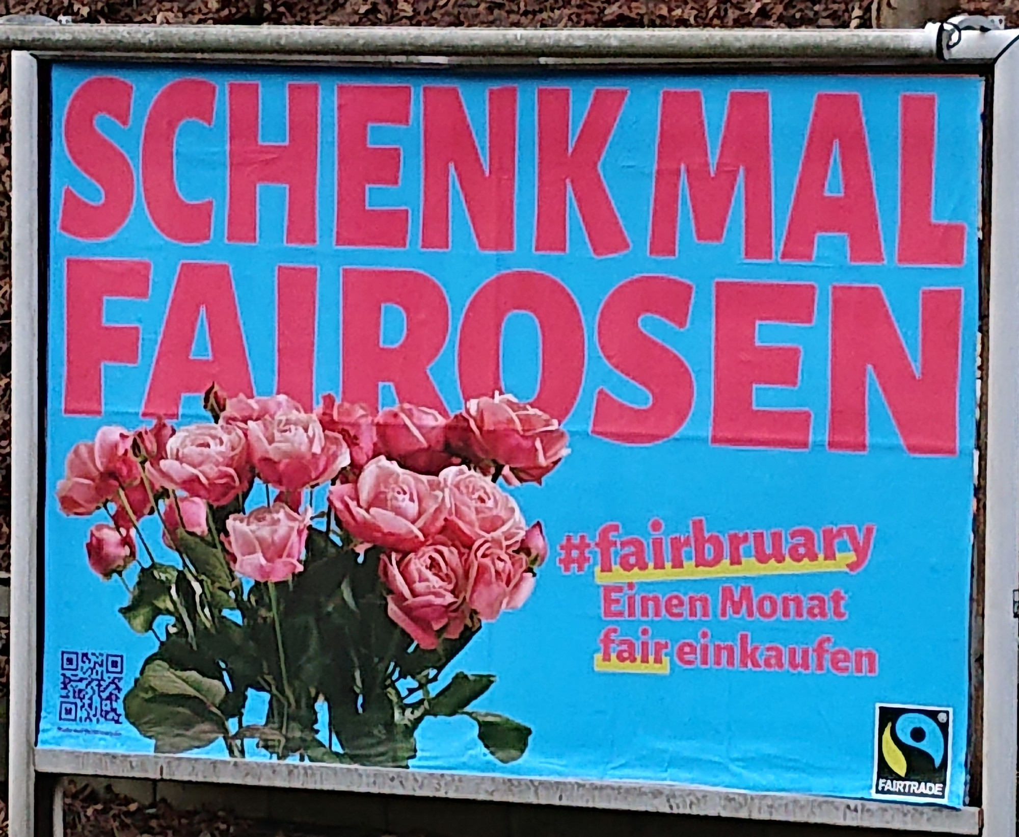 Photo of a big poster ad for a "fairbruary" campaign that encourages people to buy fairly produced goods for one month. It says "gift fairoses" in German and has a photo of roses on it.