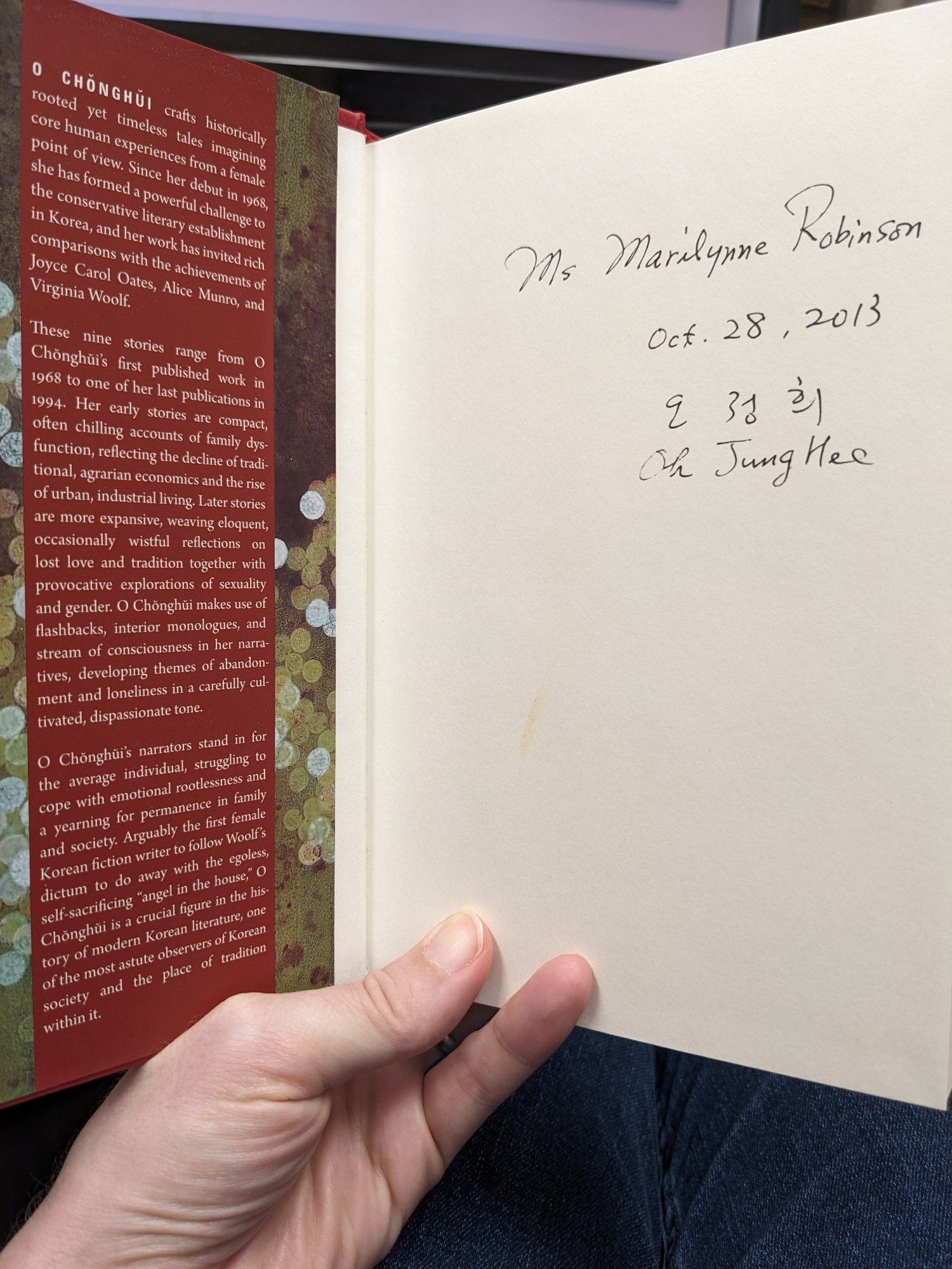 A book held open to show the front jacket flap and the front free endpaper, which is signed by the author and dated October 28, 2013