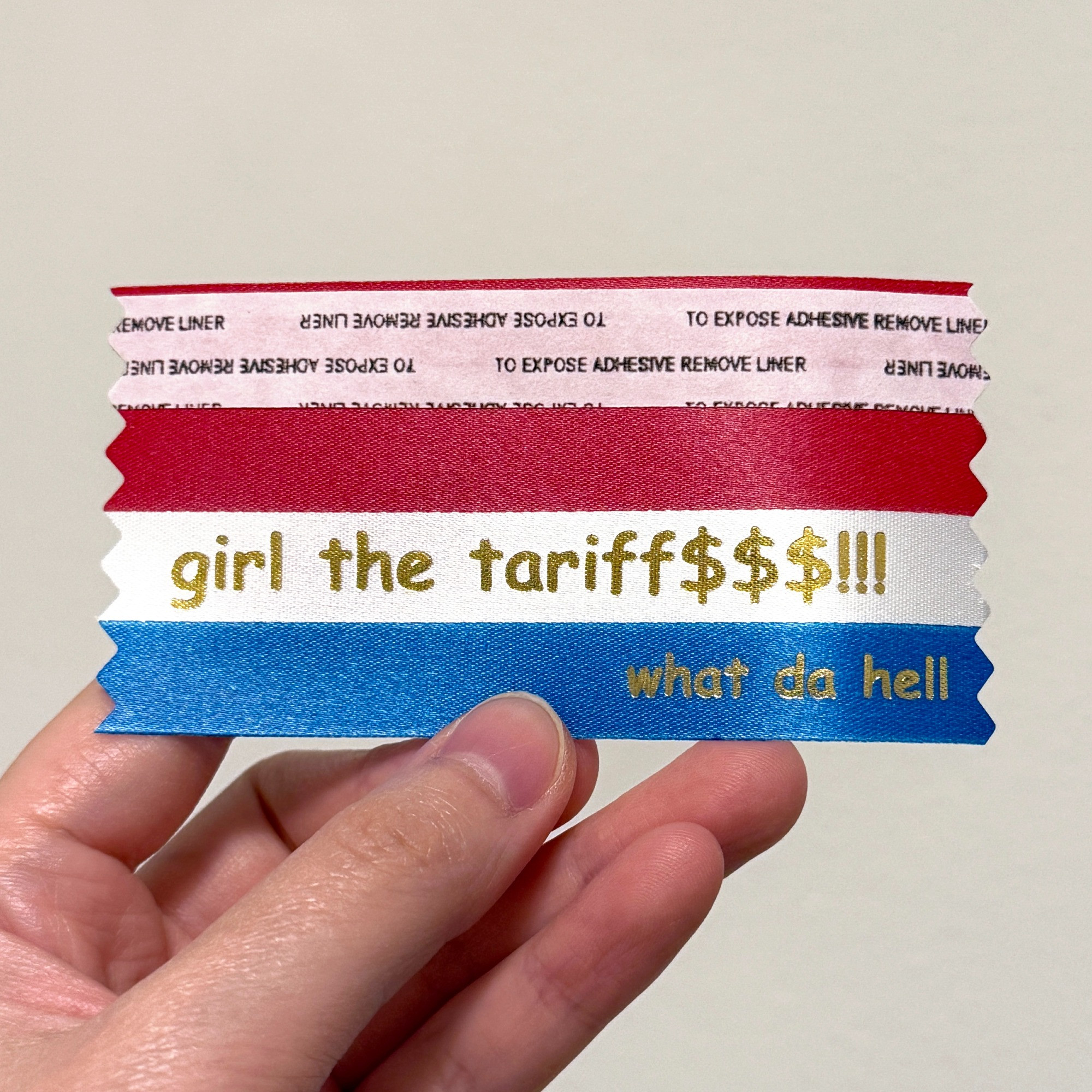 A red-white-blue badge ribbon with the text "girl the tariff$$$!!! what da hell"