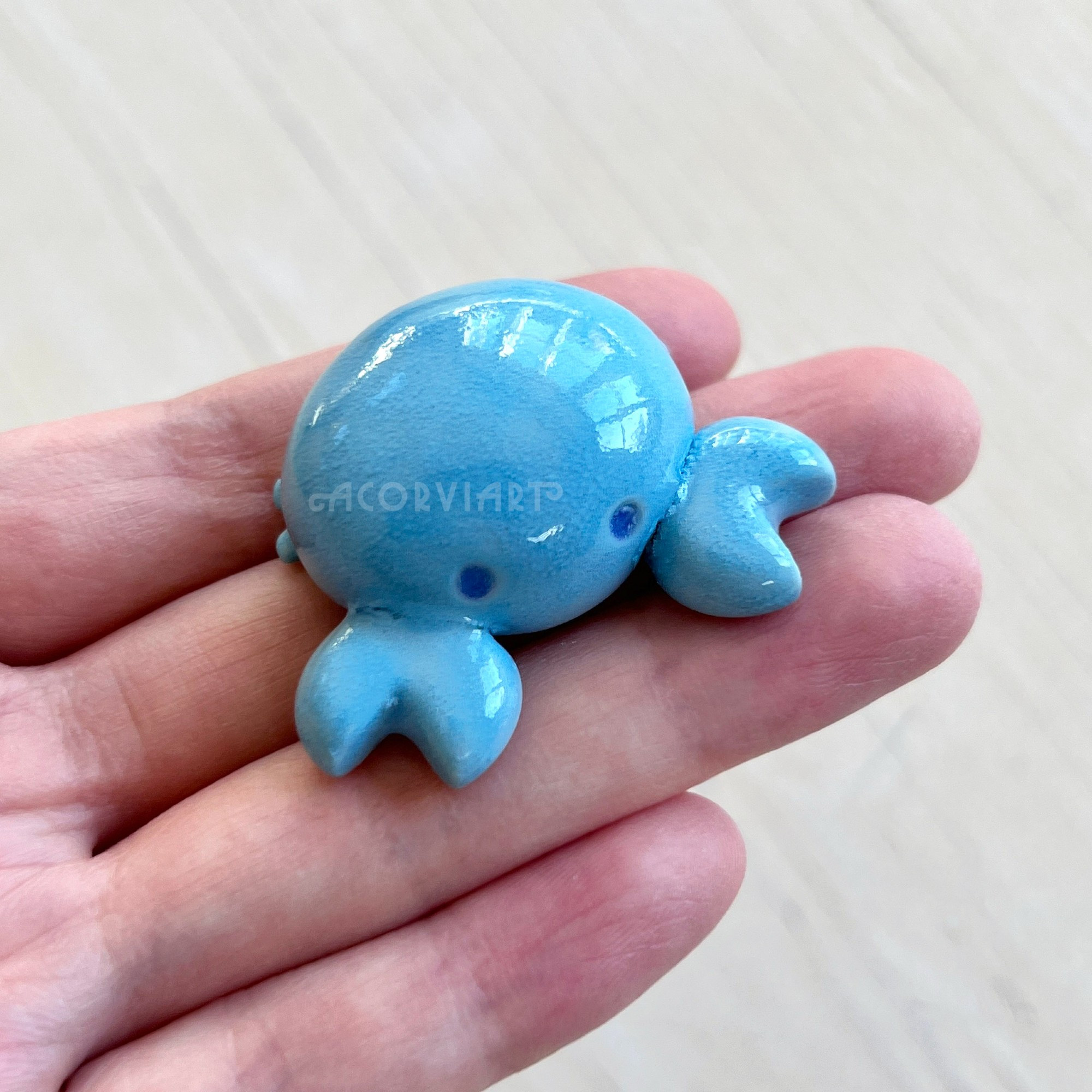 photo of a hand holding a small ceramic blue crab
