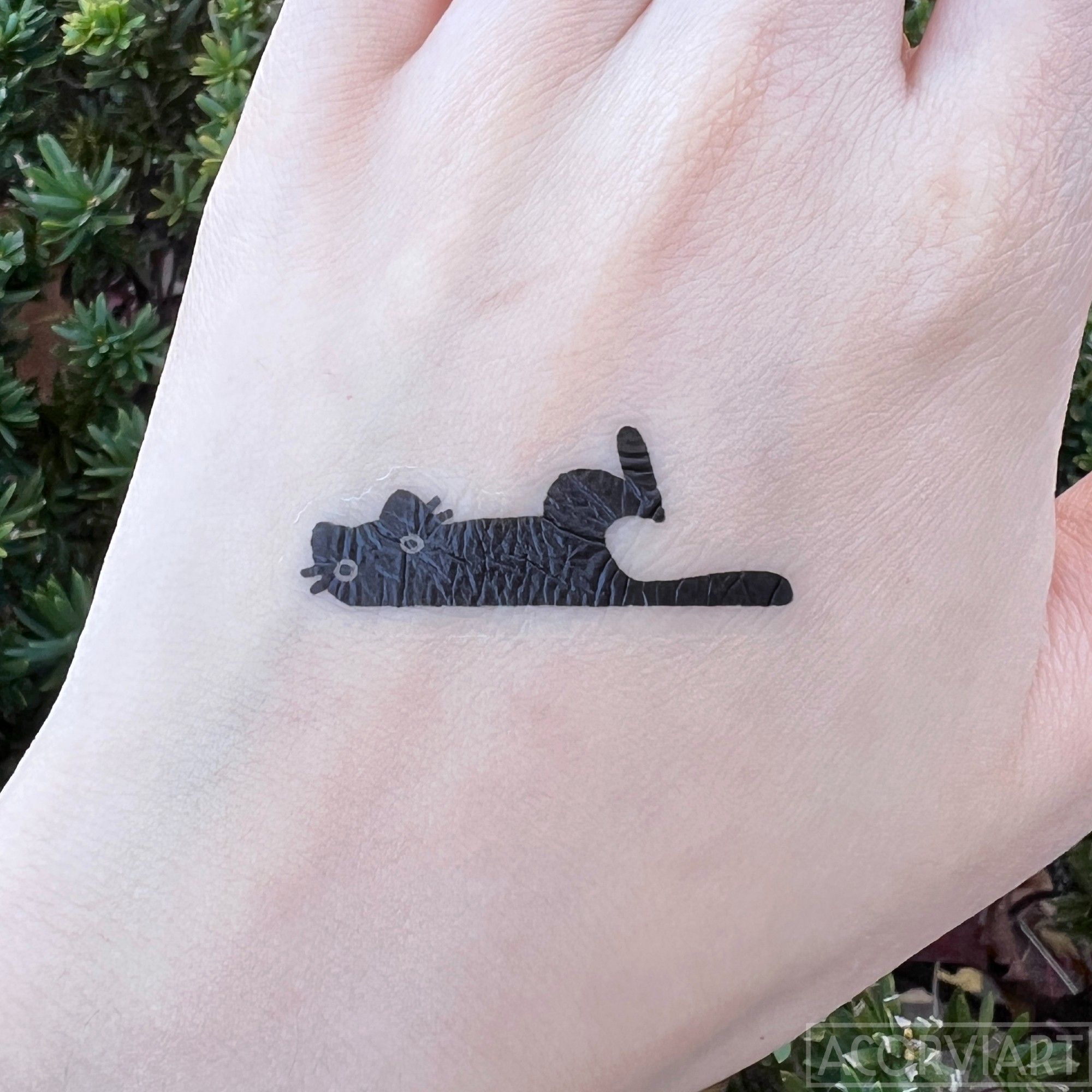 photo of a temporary tattoo of a black cat applied to the back of a hand