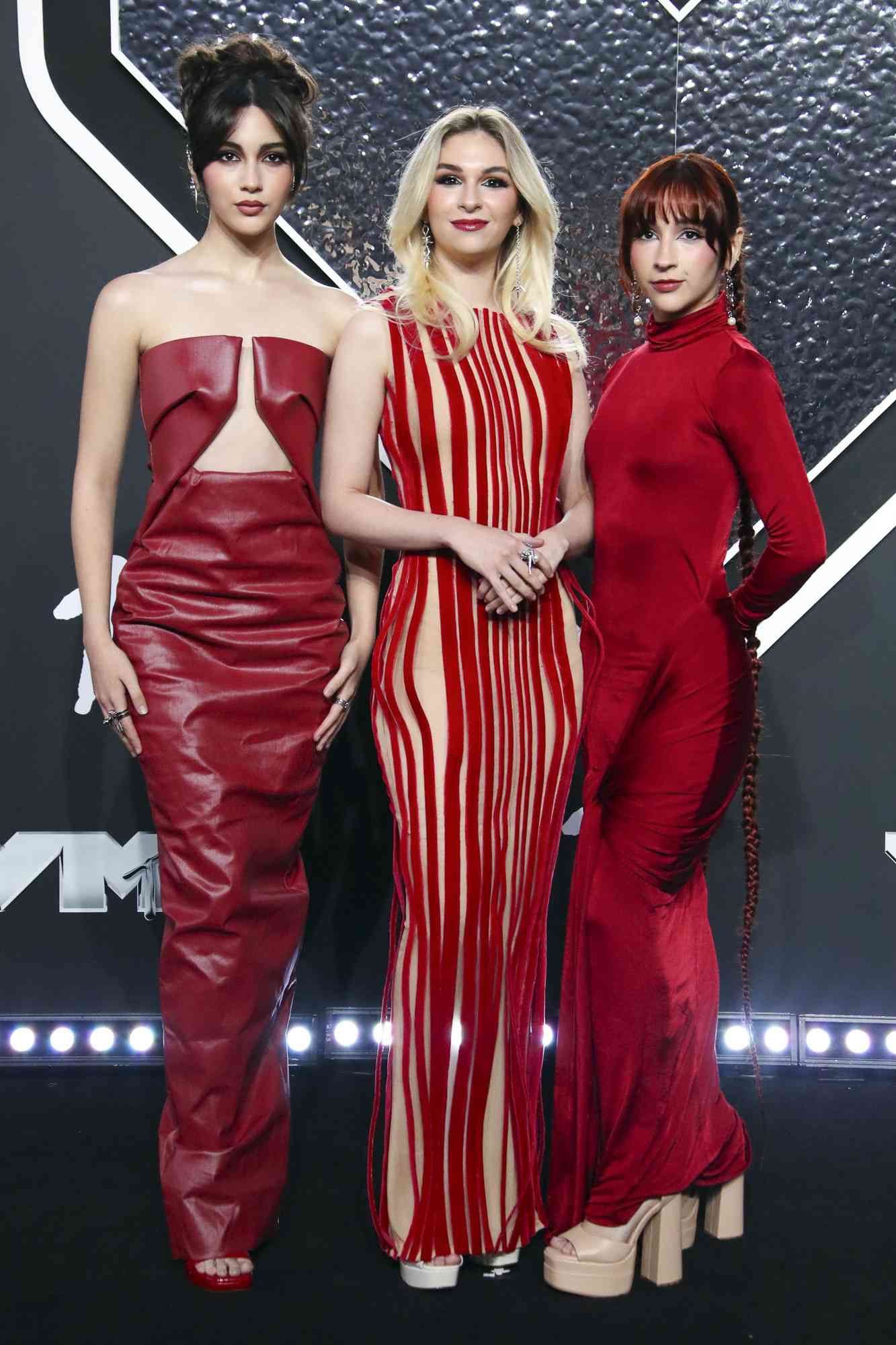 #TheWarning at the 2024 MTV Video Music Awards. From left to right: Alejandra, Daniela, and Villarreal. All three sisters are wearing dresses that are mostly or entirely red. Ale's dress is strapless and exposes her midline from neck to navel; it's identical to the black one worn by Fina Strazza when promoting Paper Girls.