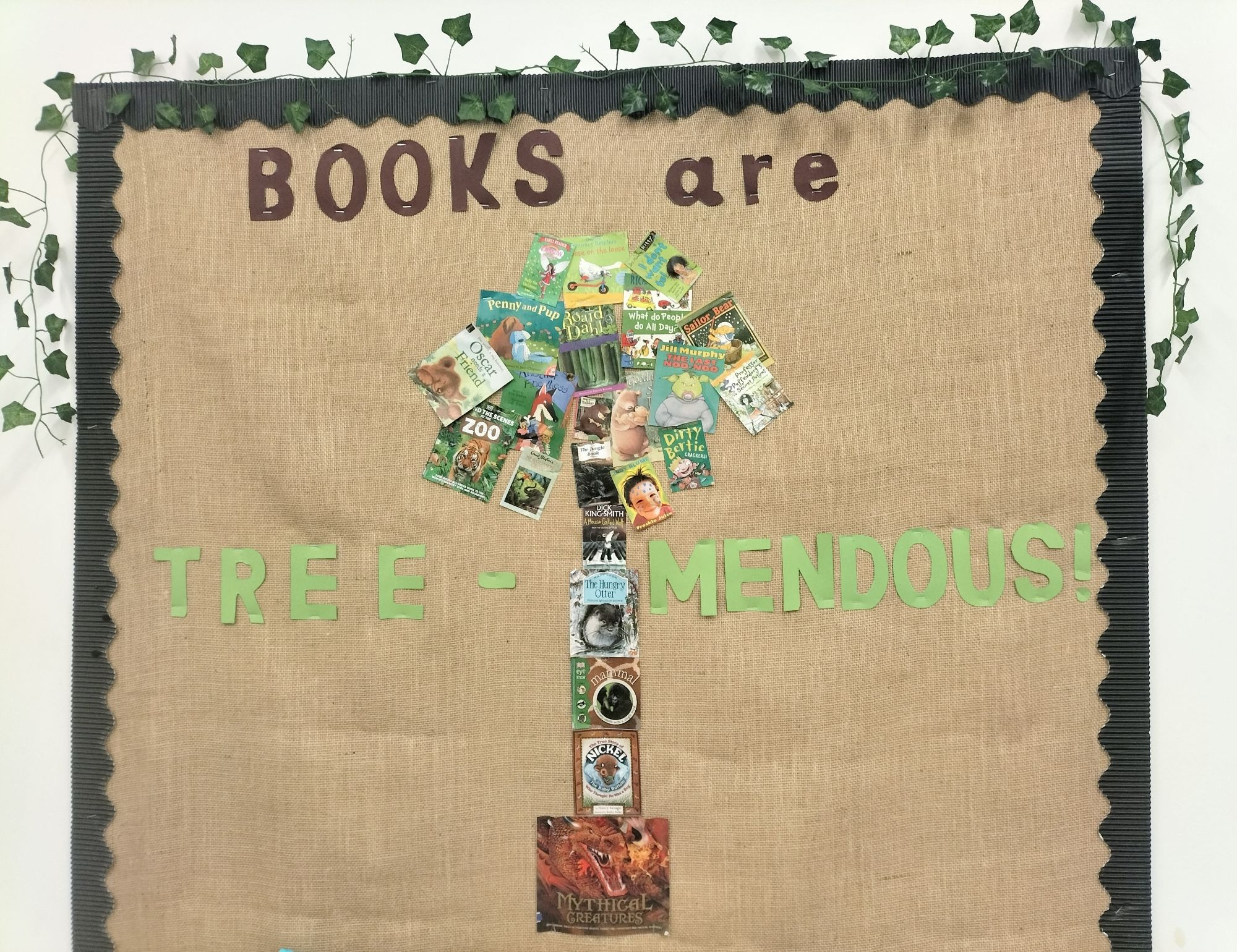 Hessian-backed school display board has a tree shape in the centre made from photocopied copies of brown and green book covers. Writing above the tree reads "Books are" and further down the board, "Tree-Mendous!"