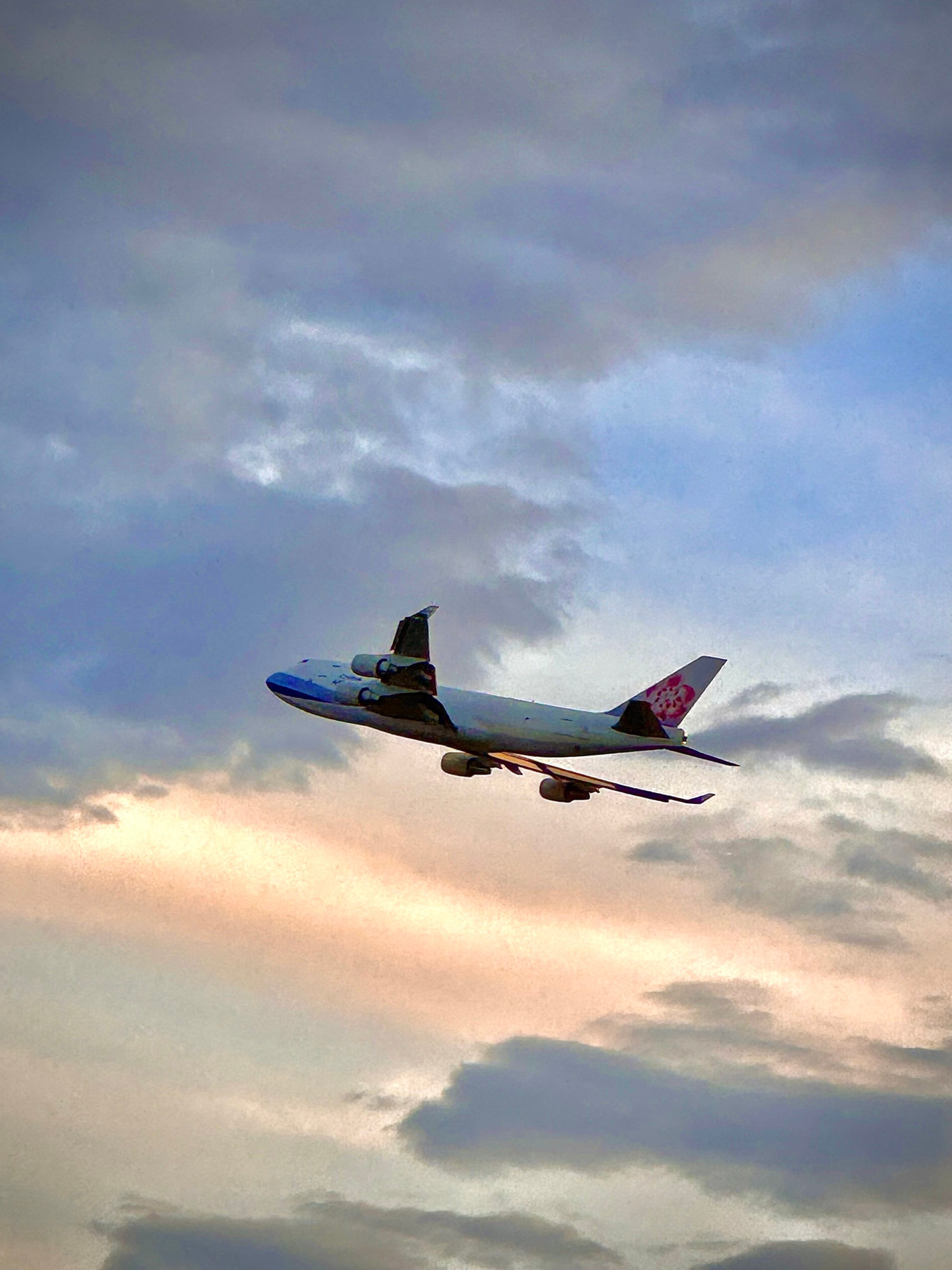 A China Airlines Cargo 747-4 freighter taking off into broken clouds in the evening sky from Runway 15 at ANC. 