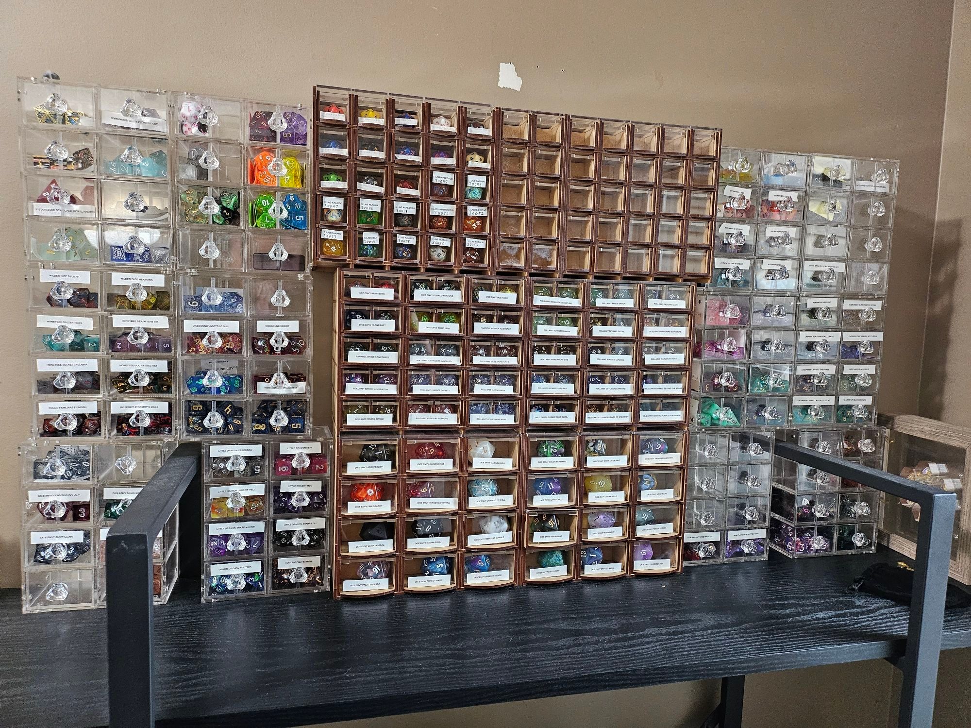 Set of display cabinets for D&D dice sets. Two columns of transparent drawers on each side flank a central section of transparent fronted wood drawers.
Roughly 18 small cabinets in all, covering a good sized shelf.