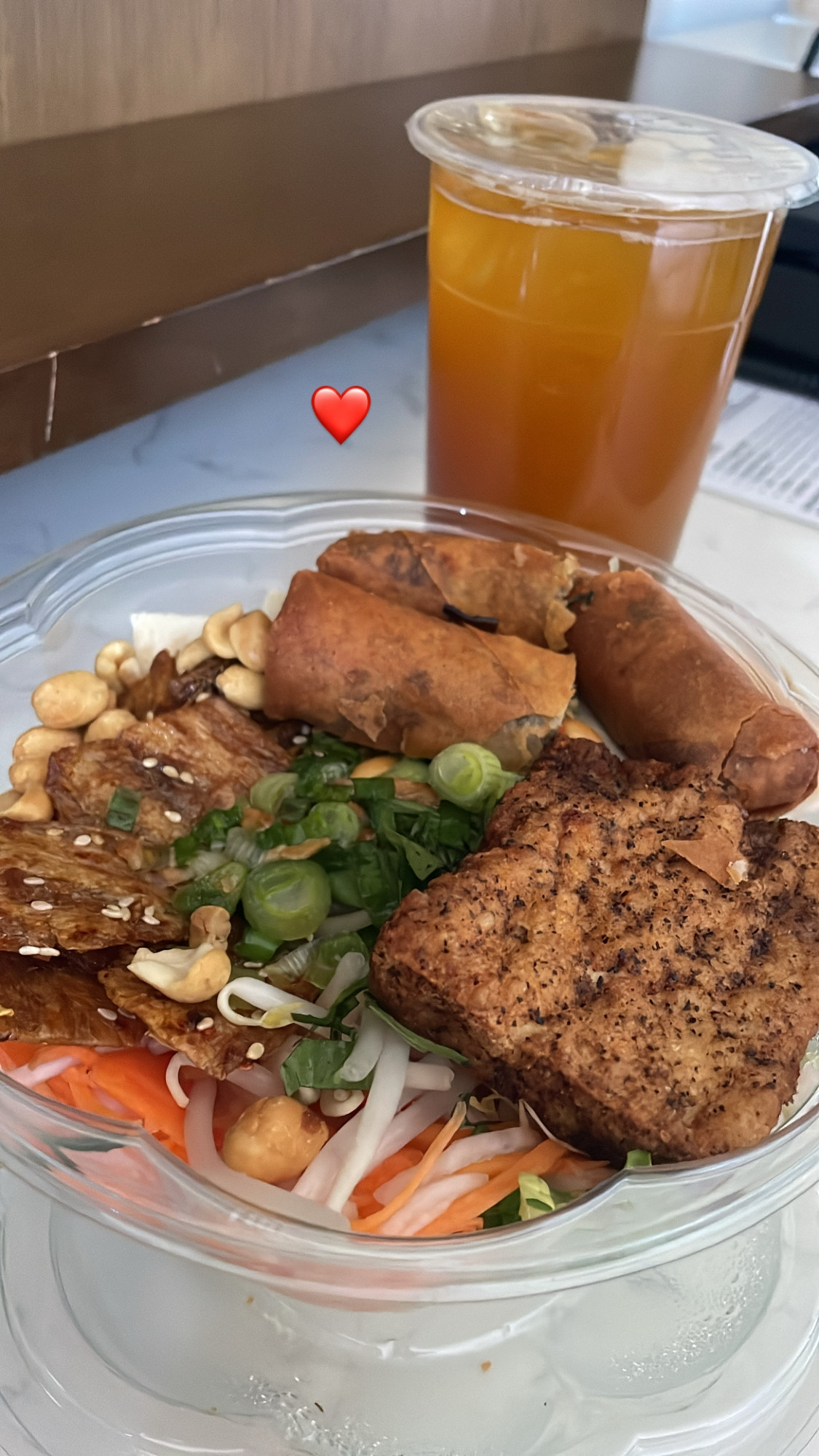 a vermicelli noodle bowl topped with carrots, daikon, and peanuts. on top of that, tried tofu skins, egg rolls, the best salt and pepper tofu i've ever had in my life, and some scallions. plus an iced tea