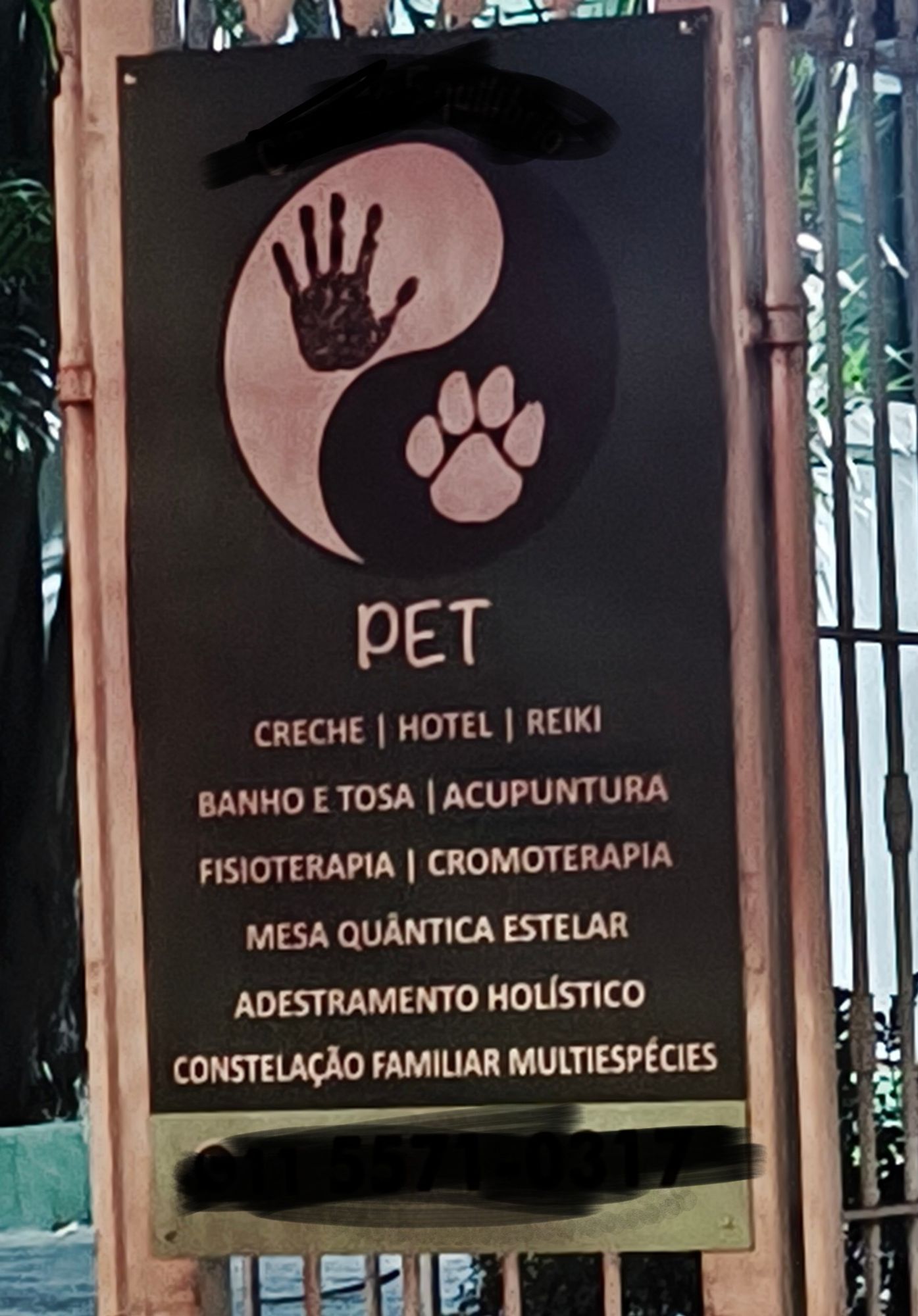 Placa de divulgação dos serviços de um pet shop. Entre eles mesa quântica estelar, adestramento holístico e constelação familiar multiespecies