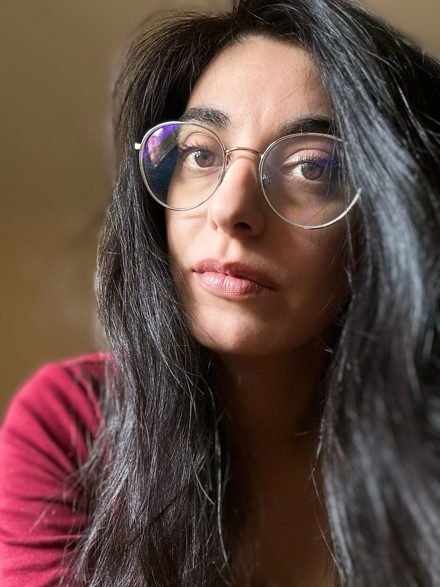 Selfie di donna con occhiali da vista e capelli neri sciolti.