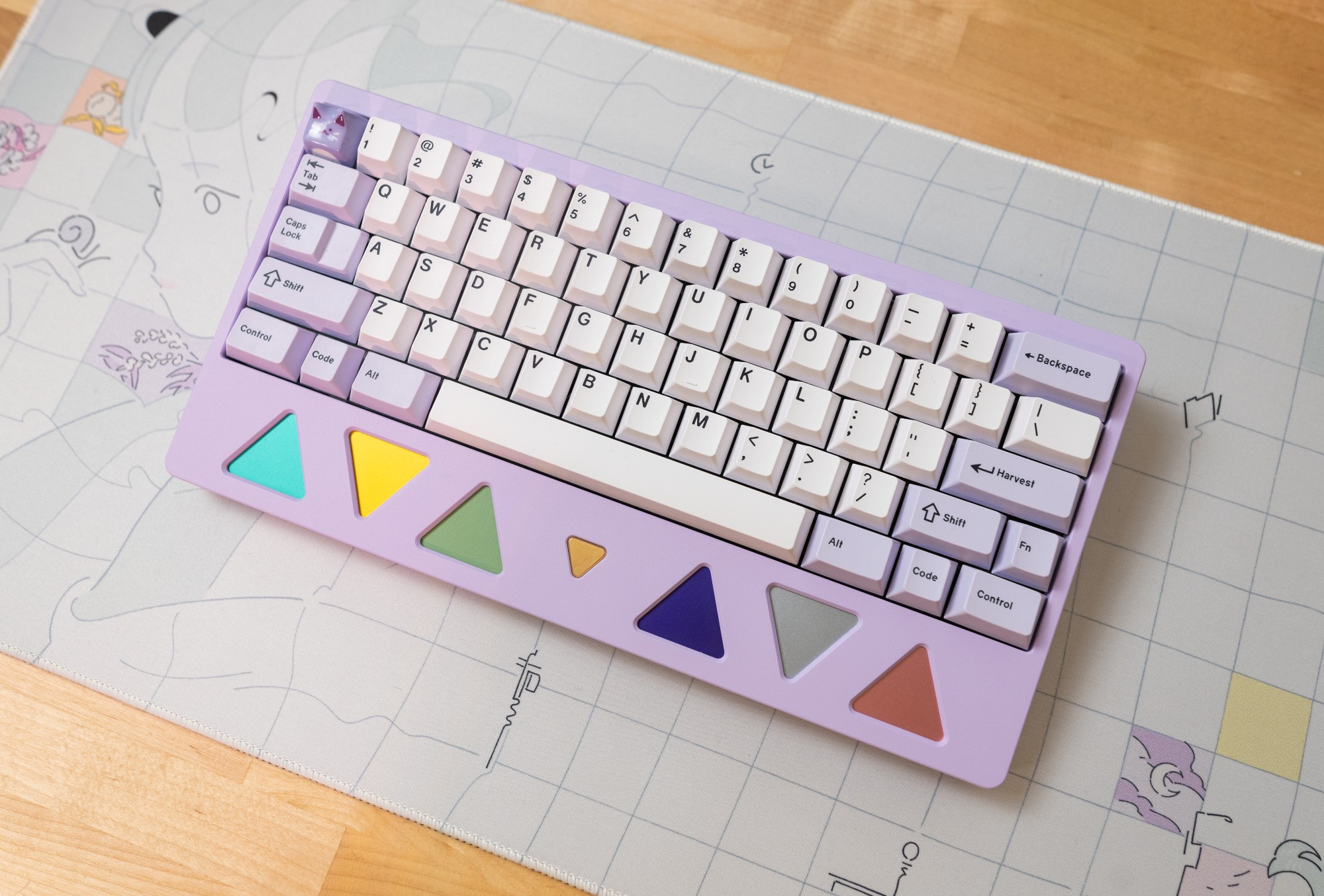 60% keyboard in lavender called the Trigon with a built in wrist rest with colored triangle blocks with lavender and white keycaps