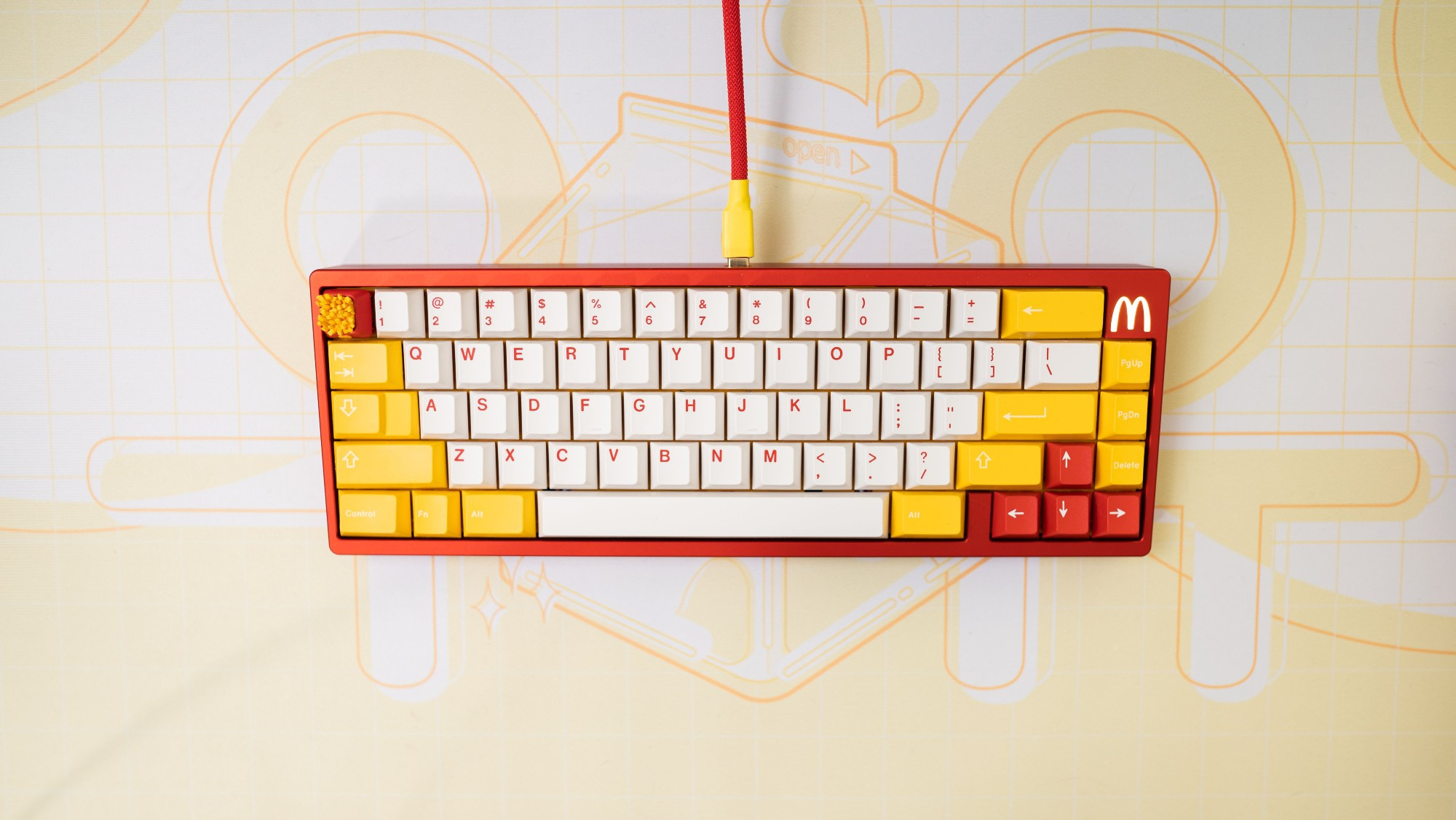 McDonald color themed keyboard called the Mc65, red keyboard base with yellow + white keycaps with a McDonald's logo in the top right hand corner