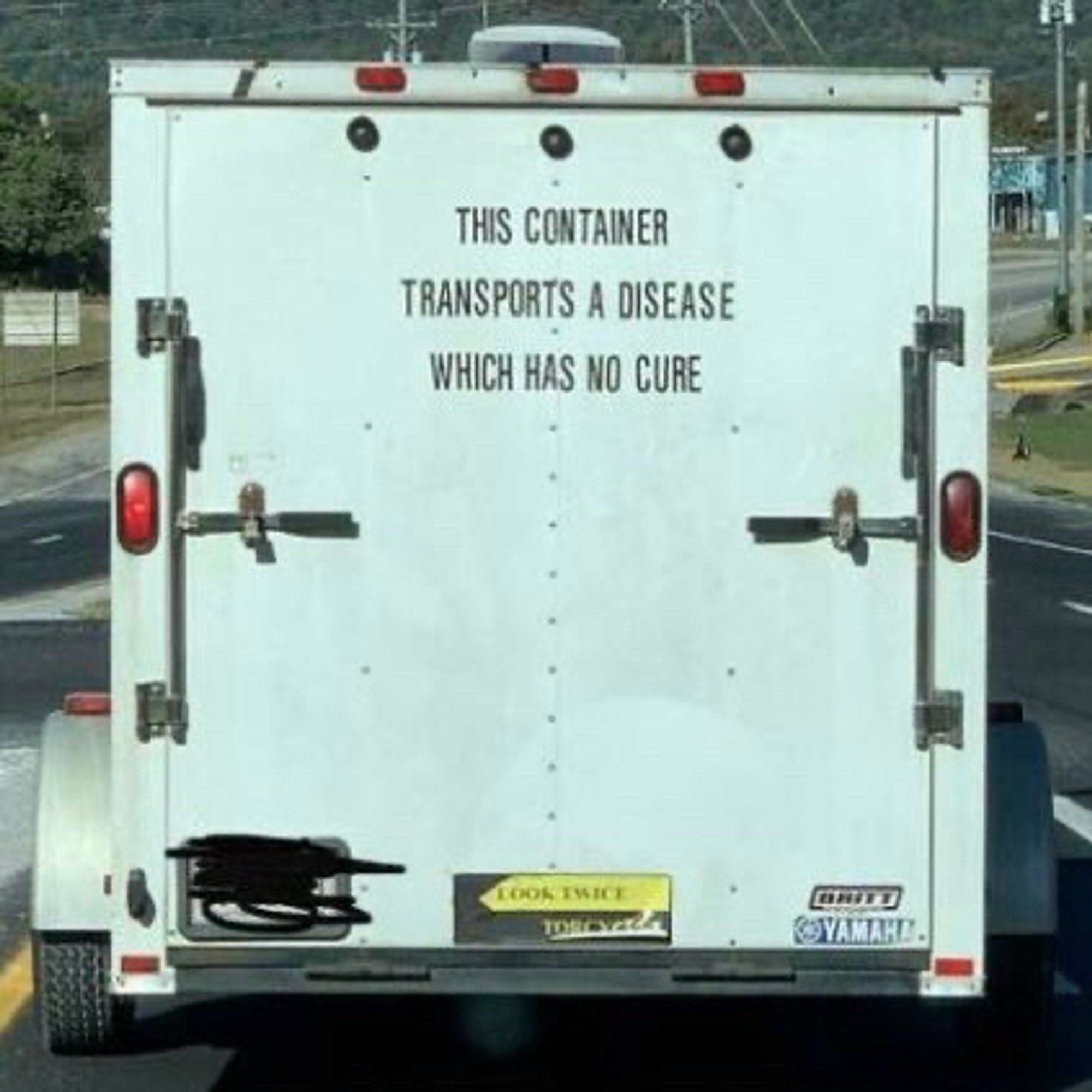 White cargo trailer with a message that reads "THIS CONTAINER TRANSPORTS A DISEASE WHICH HAS NO CURE."