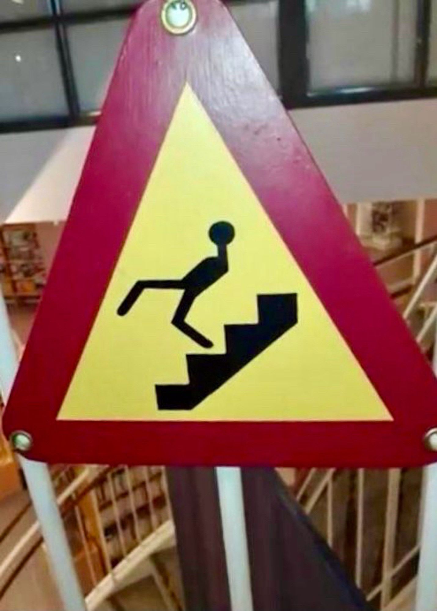 Caution sign with silhouette of a person walking down the stairs similarly to John Cleese in the Ministry of Silly Walks skit.