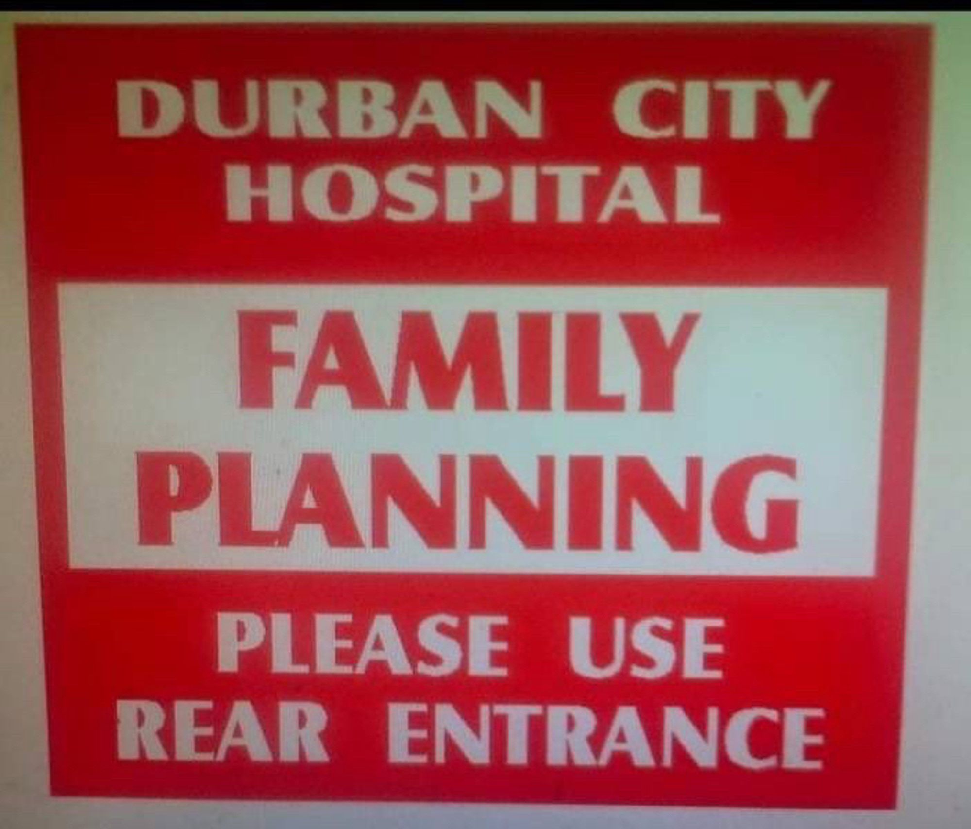 Red and white sign reads “Durban City Hospital, Family Planning, Please Use Rear Entrance.”