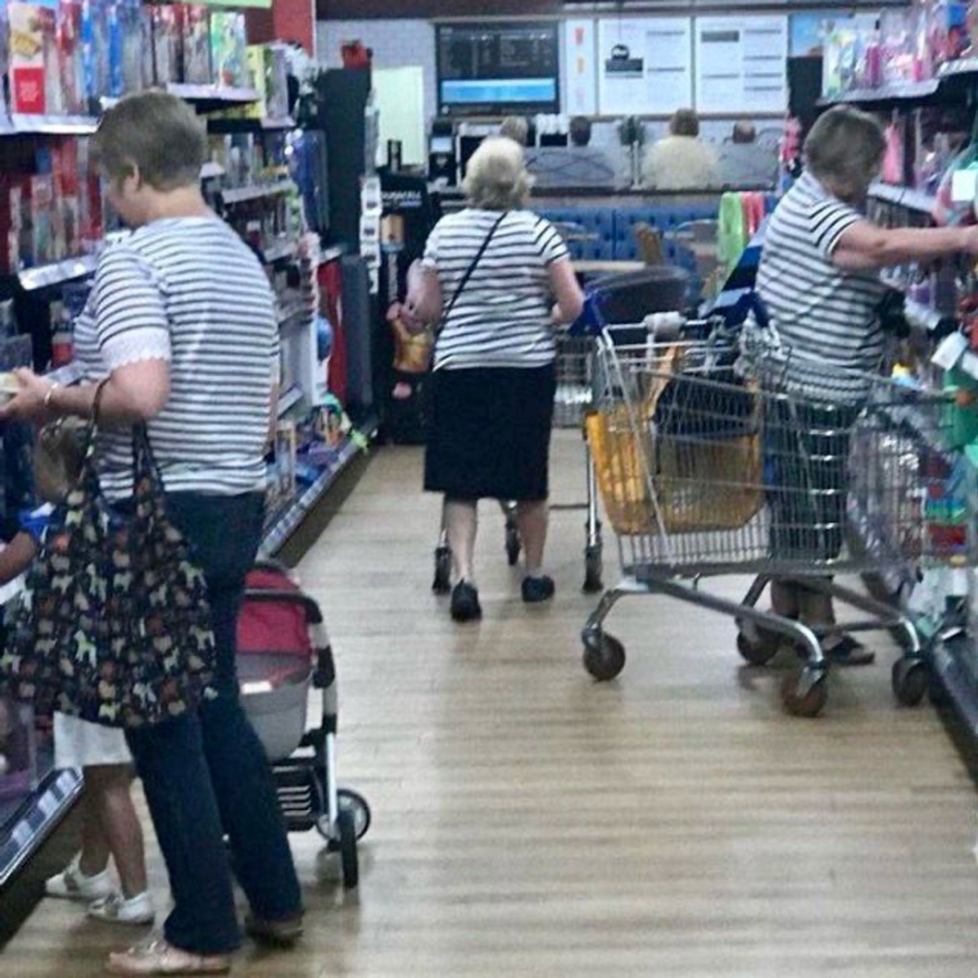 The image shows three older women in a store aisle wearing very similar striped shirts. Two women are pushing shopping carts, while one woman is interacting with a child. The store shelves are filled with various products.