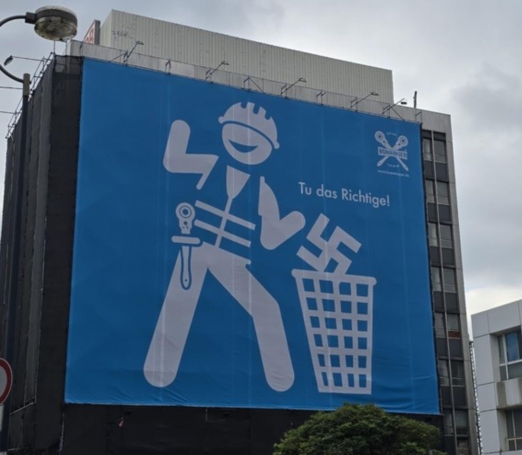 Werbe Plakat über die ganze Front eines Hochhaus in Dortmund.
Darauf zu sehen ein Comic Handwerker der ein Hakenkreuze in eine Mülltonne wirft.
Übertitelt mit dem Schriftzug "Tu das Richtige"