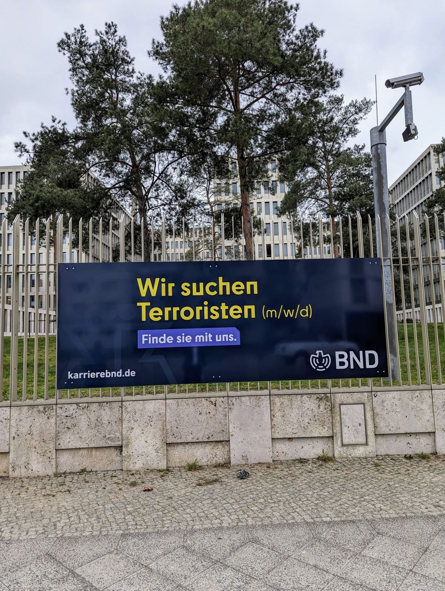 Ein Werbebanner am Zaun der BND Zentrale in Berlin Mitte.
Aufschrift "Wir suchen Terroristen (m/w/d)
Finde sie mir uns.
Karrierebnd.de