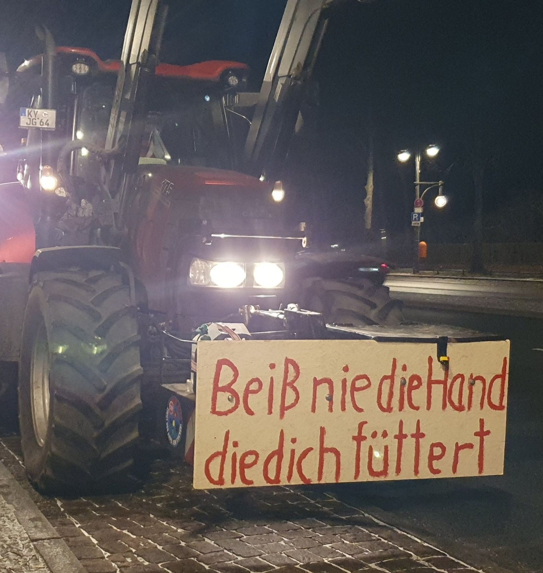 Traktor mit "Beiß nie die Hand die dich füttert" Plakat im Tiergarten.