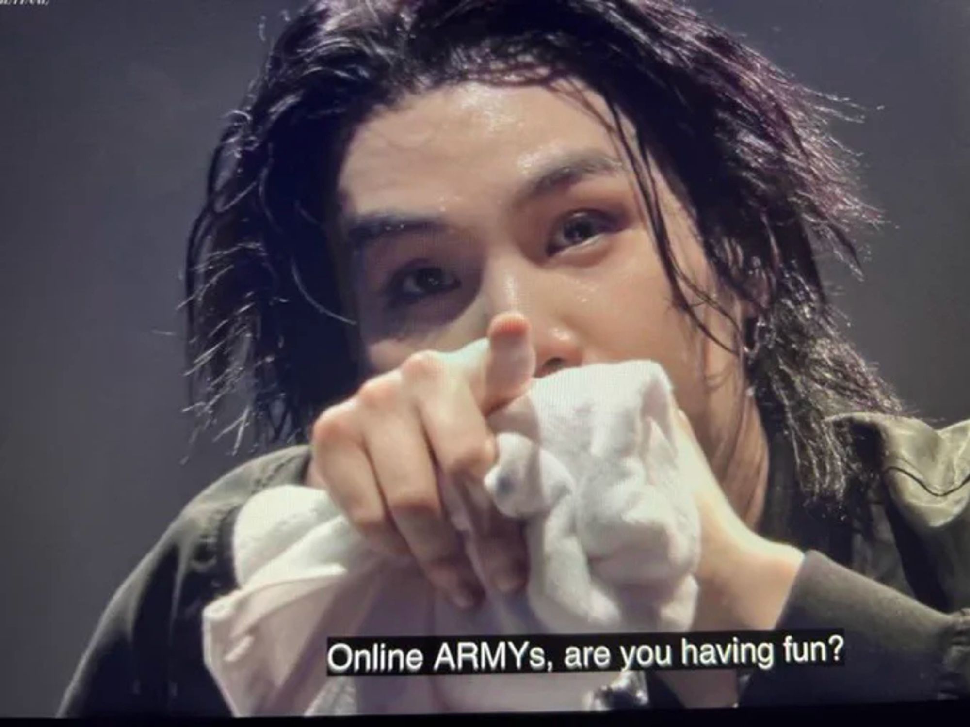 Picture of Yoongi / Suga / Agust D pointing a finger at the camera with  a towel in the pointing hand and the subtitles "Online ARMY are you having fun?" on the screen at his Agust D D-day Final concert day 1 in Seoul, Korea