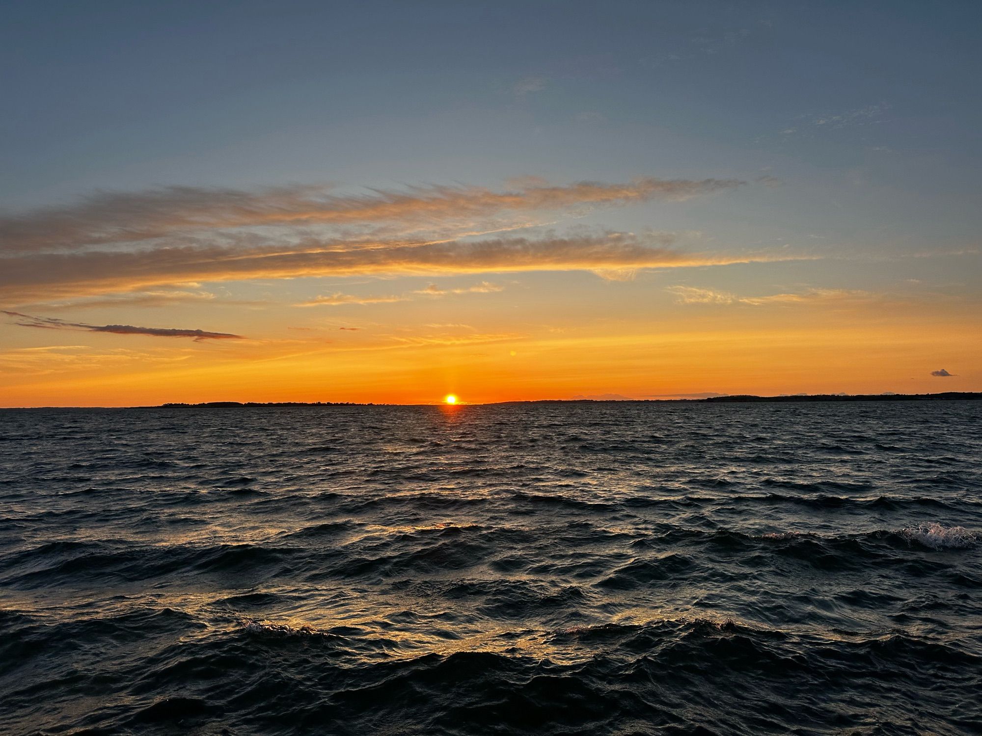 Blick von einem Boot aus auf einen Sonnenuntergang über der Küste