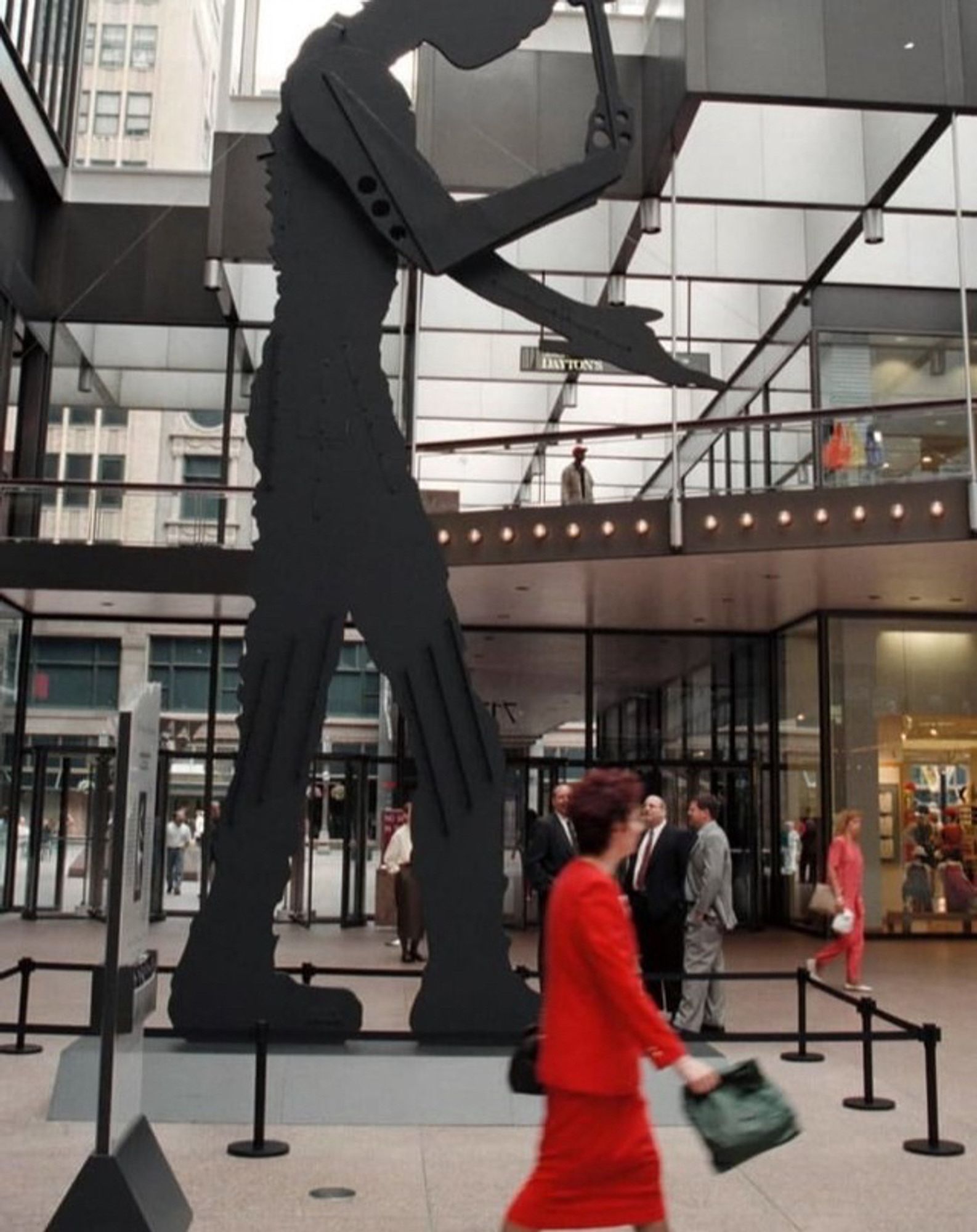 large metal silhouette of a standing figure with a hammer, in a downtown atrium