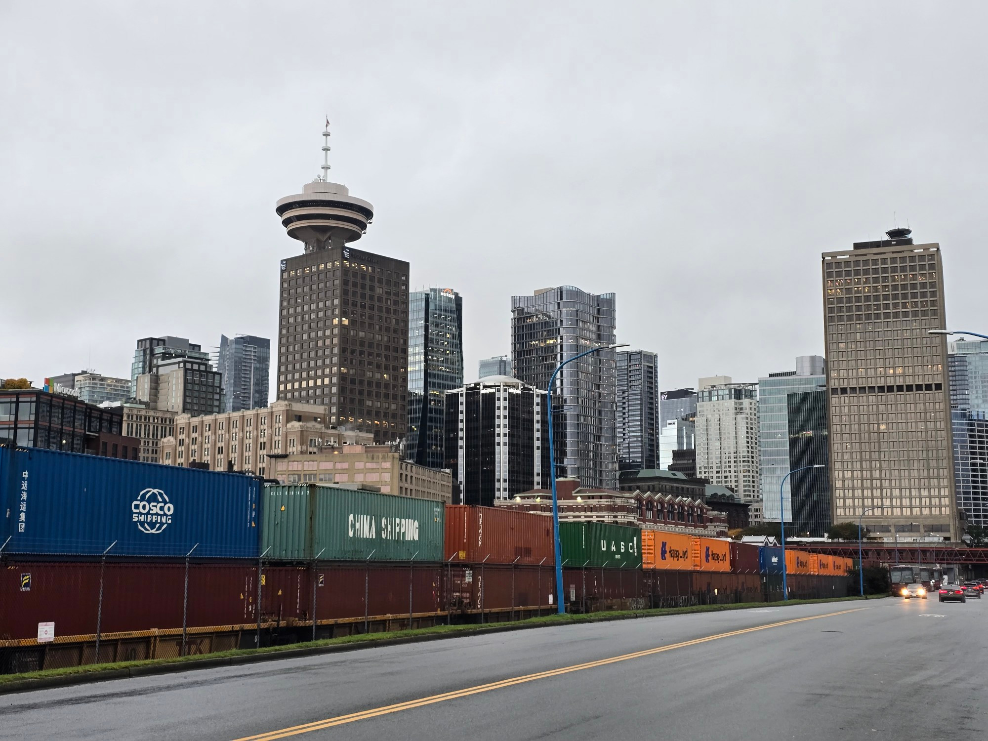 A shot of the Harbour Centre and a Misty/rainy looking downtown Vancouver from Waterfront Rd, with a line of double stacked containers on rail cars in the foreground.