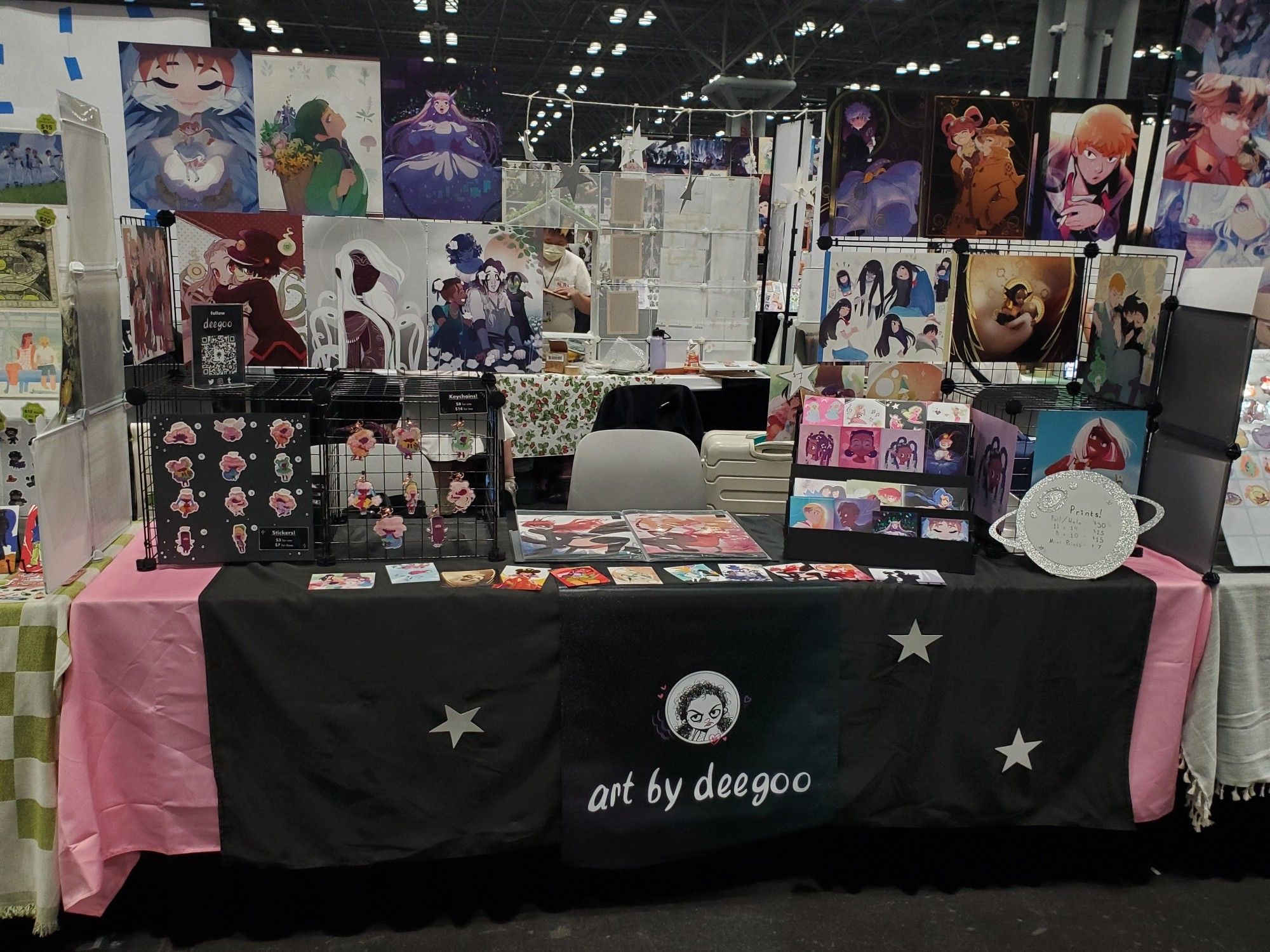 An artist alley table with keychains and prints