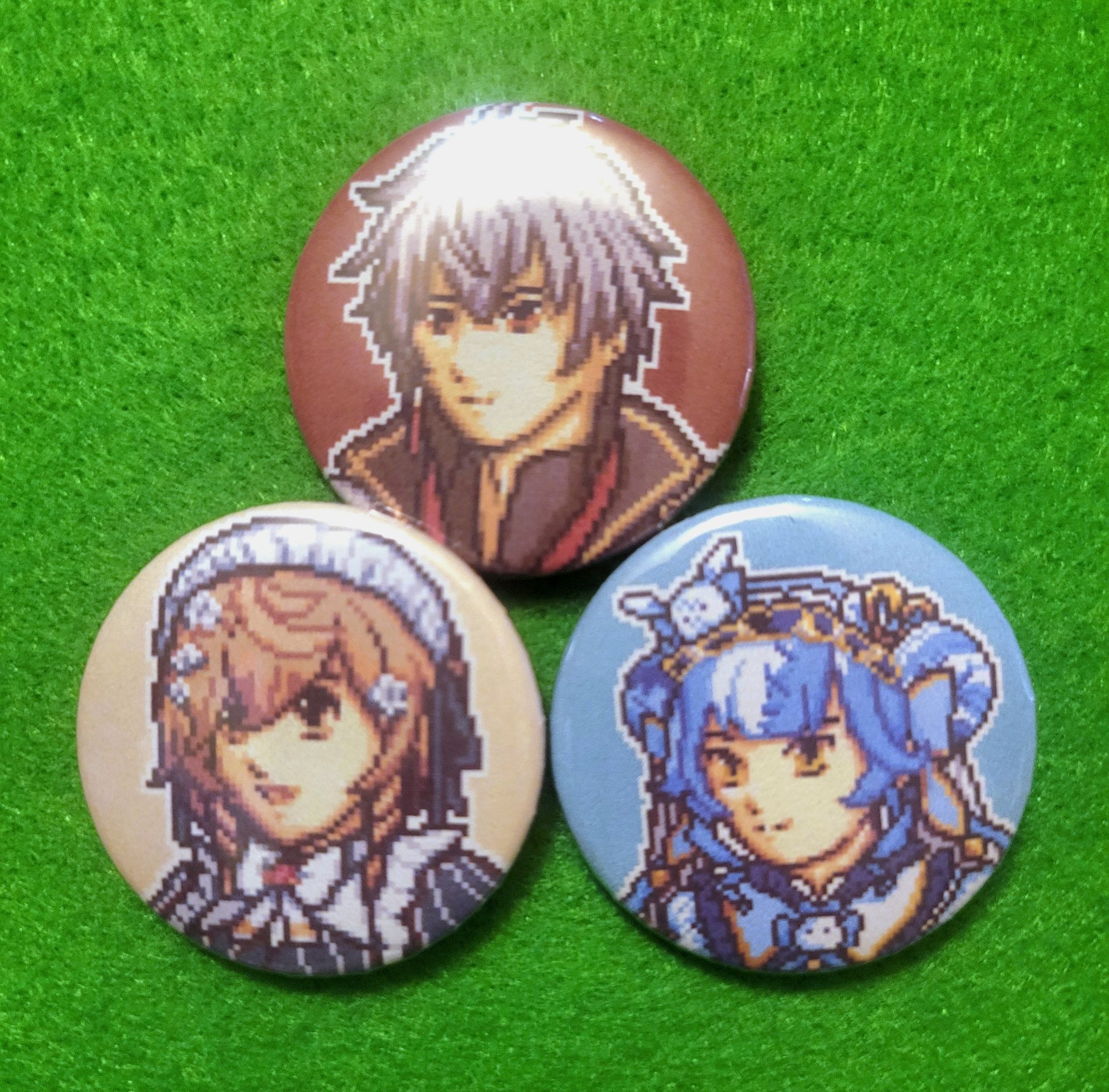 Three pinback buttons depicting Nijisanji EN VTubers Ryoma Barrenwort, Klara Charmwood, and Twisty Amanozako on a green background. The characters are drawn in a pixelated style similar to the GBA Fire Emblem games