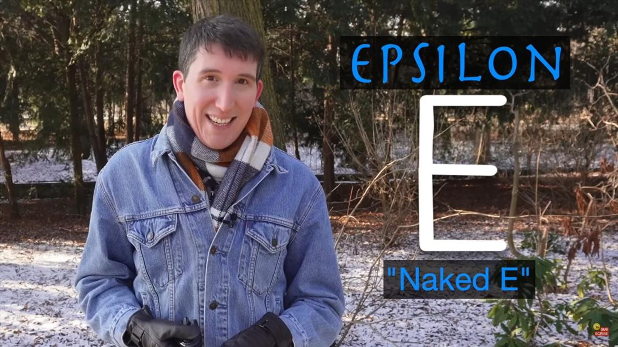 Screenshot: Rob, wearing a denim jacket and black leather gloves, stands hatless in a wooded area that's dusted with snow. A graphic overlaid on the screen reads: "'Epsilon' [E-symbol] 'Naked E'"