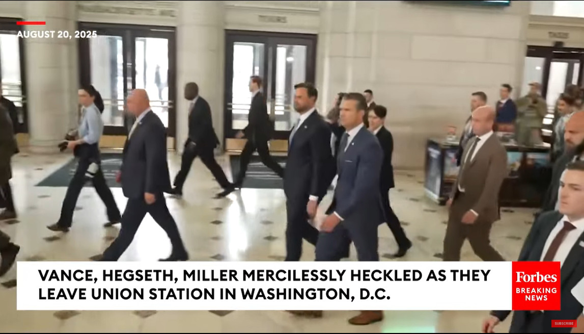 screenshot of a Forbes breaking news video; chyron reads "Vance, Hegseth, Miller mercilessly heckled as they leave union station in washington DC"