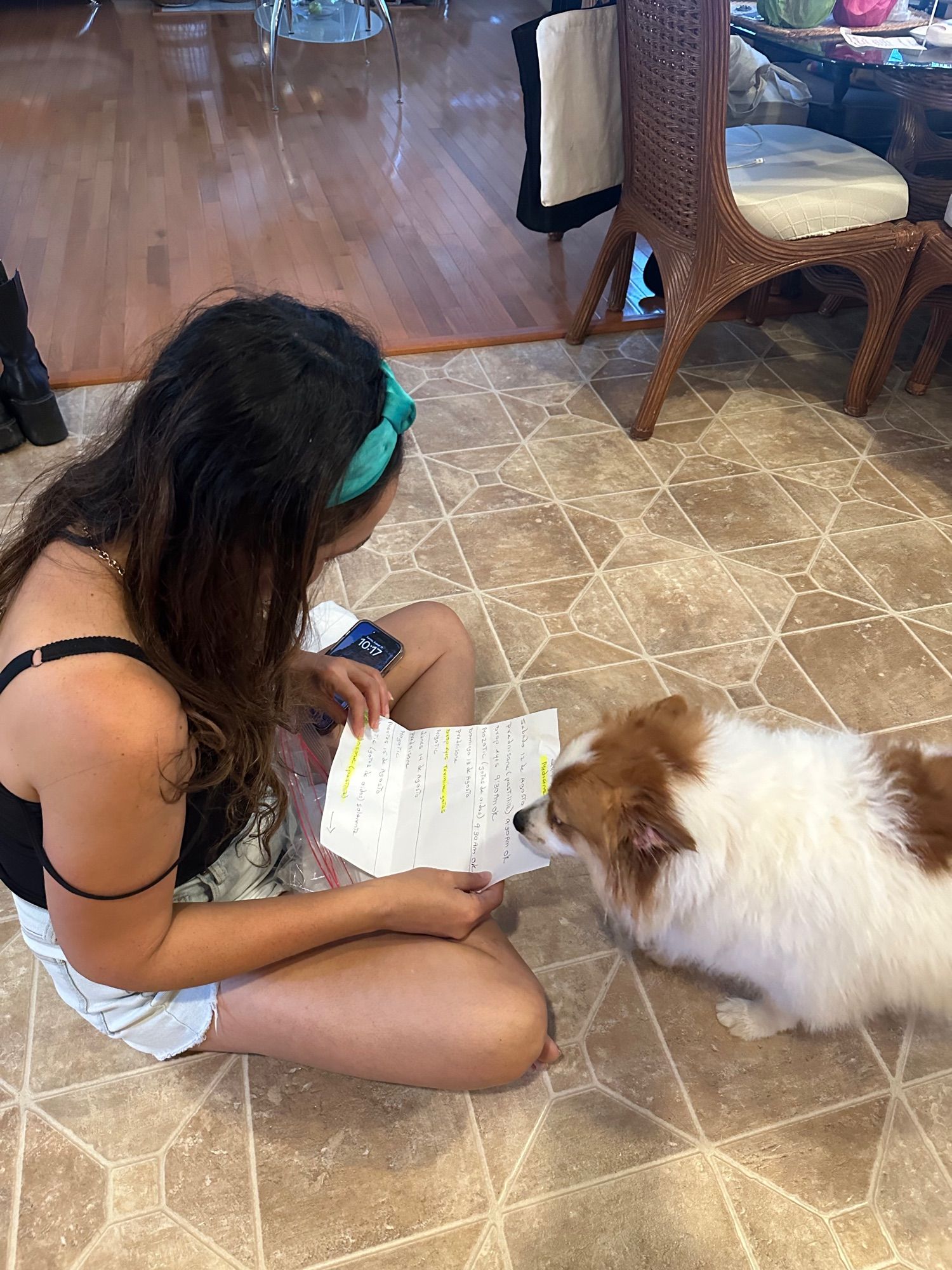 Lady on the floor holding a paper with instructions and the dog reading the paper 