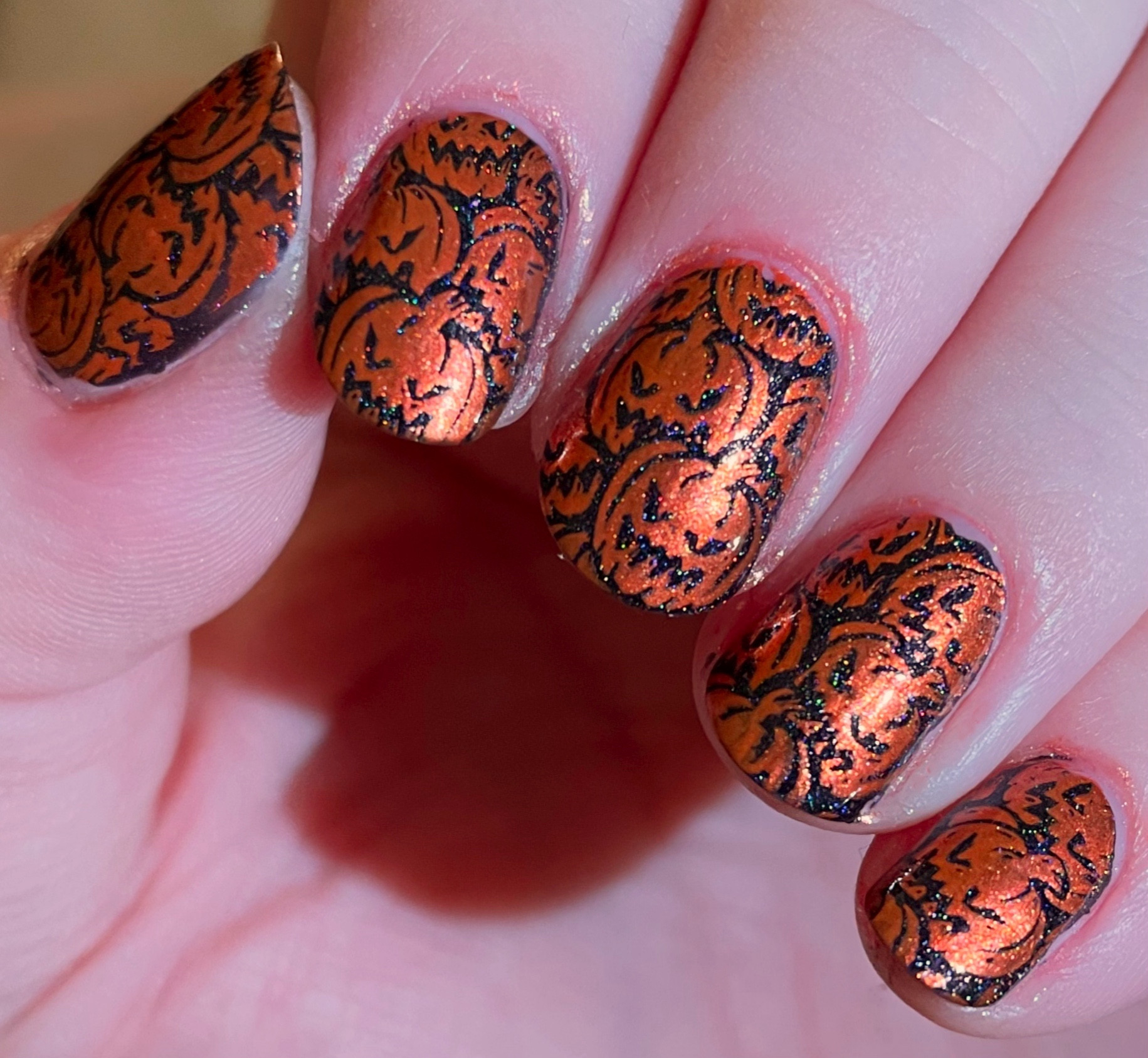 Photo of nailart, a black holographic base with shimmery orange halloween pumpkins on top