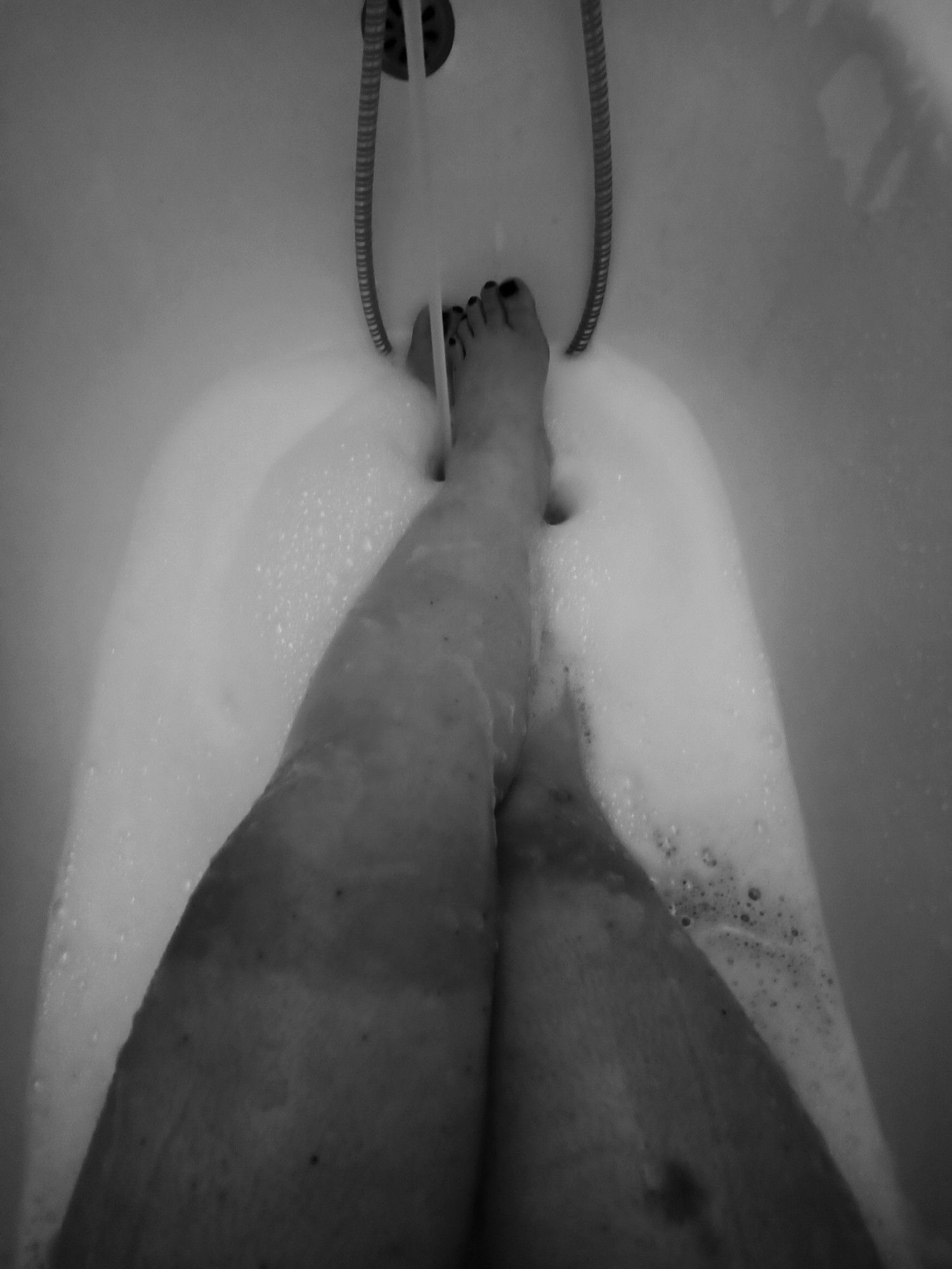 Beltanes Beine von oben in der Badewanne mit viel Schaum fotografiert. Oberhalb der Knie sieht man deutlich, wo die Radler-Hosen enden. Man nennt das Profi Kante. 
Schwarzweiß Bild