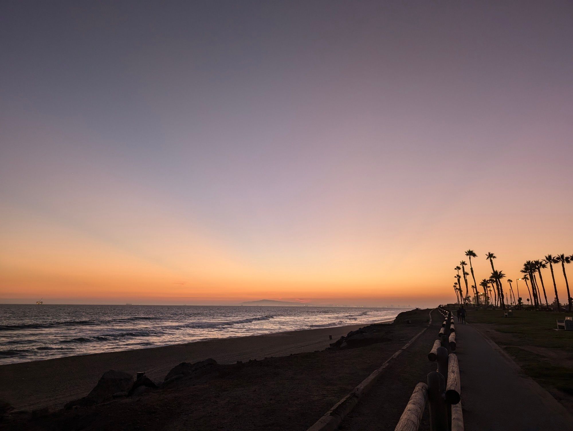 a photo of a beach at dusk. The sun has fallen below the horizon but you can still see beams of light in the sky