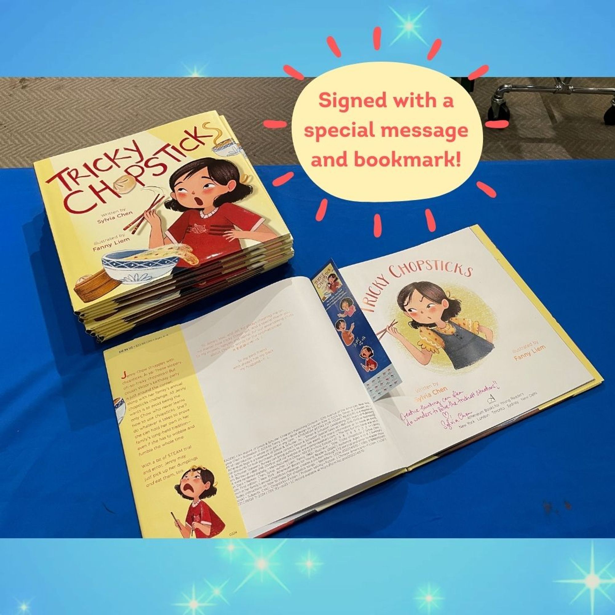 Picture of an open, signed copy of TRICKY CHOPSTICKS with a special message plus bookmark tucked in, next to a stack of signed copies of TRICKY CHOPSTICKS.