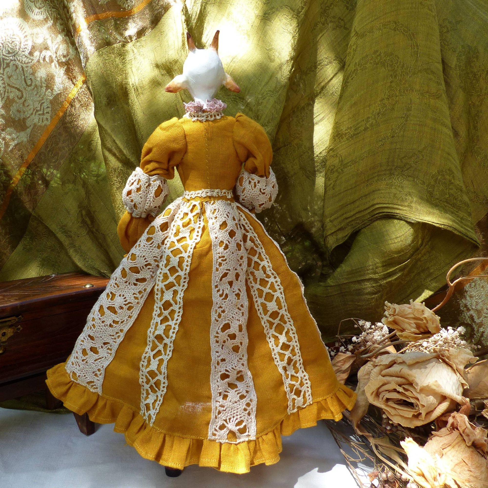 back facing full body picture of an anthropomorphised white goat doll, wearing a mustard yellow dress with cream lace accents (very cottage core)