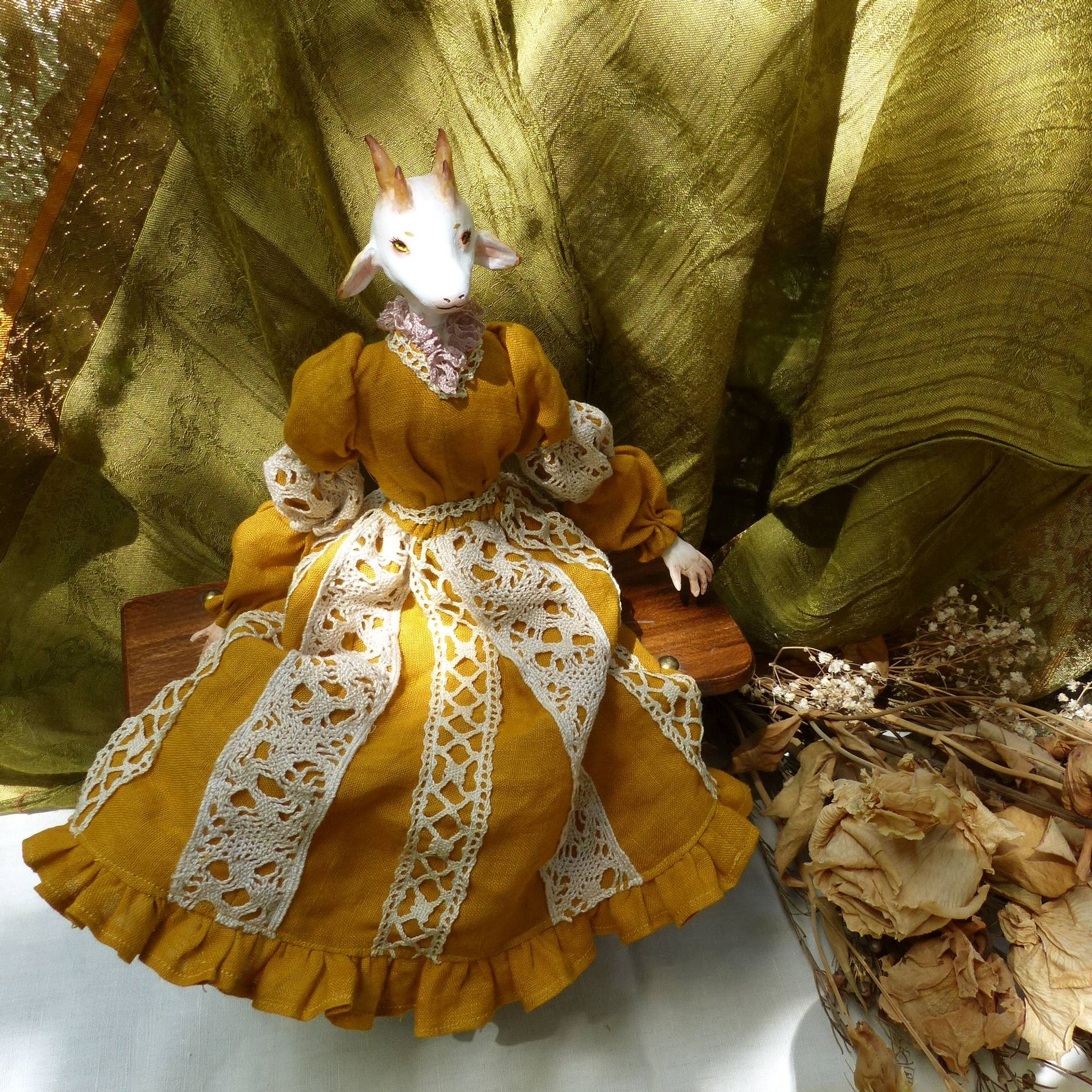 full body picture of an anthropomorphised white goat doll, sitting down, wearing a mustard yellow dress with cream lace accents (very cottage core)