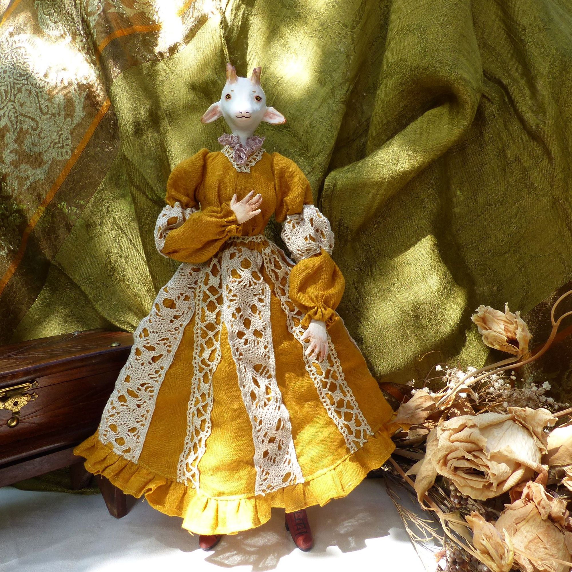 front facing full body picture of an anthropomorphised white goat doll, wearing a mustard yellow dress with cream lace accents (very cottage core)