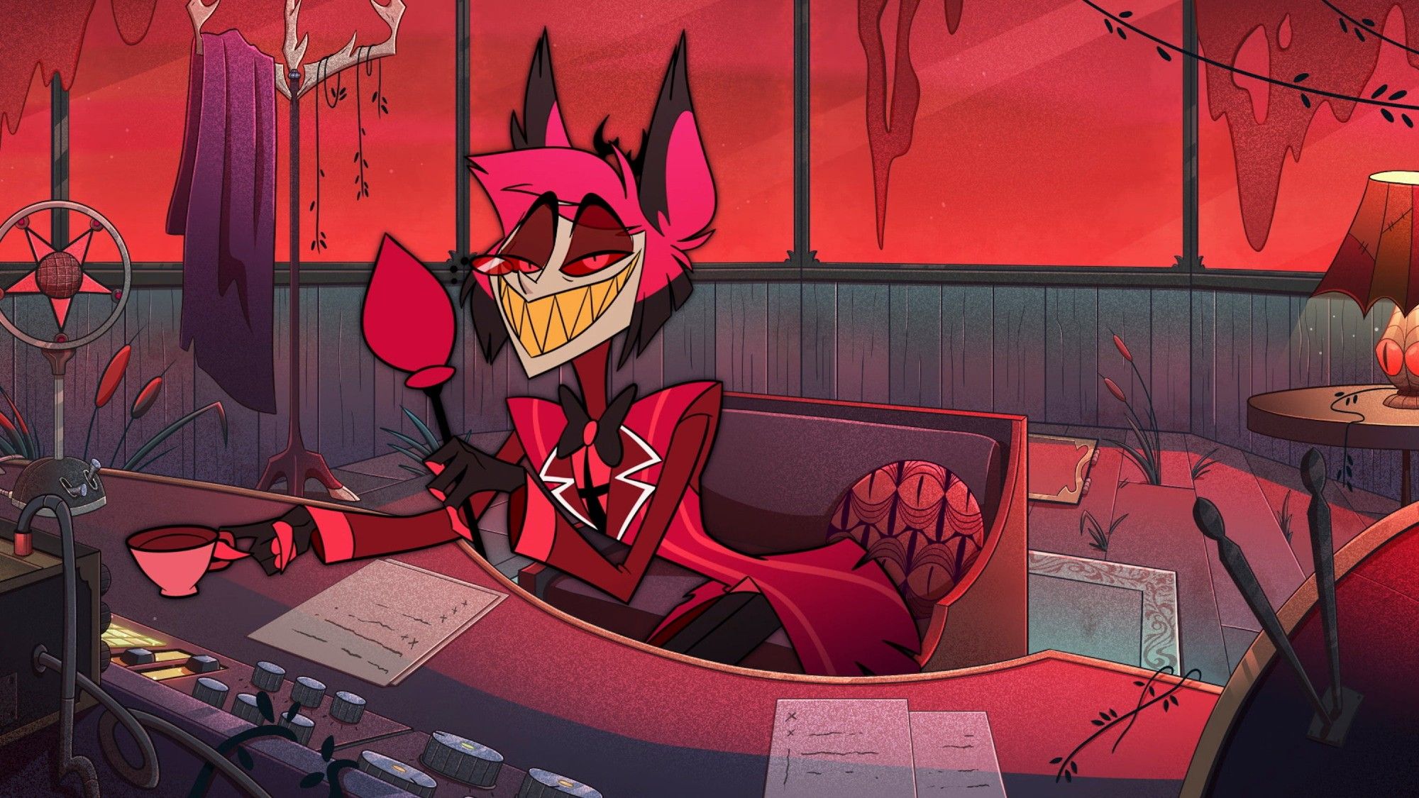 Art of Alastor taking a seat at his radio tower desk. He has short black and red hair, along with deer ears and very tiny antlers. He's speaking into his mic using one hand, a cup of tea in the other.