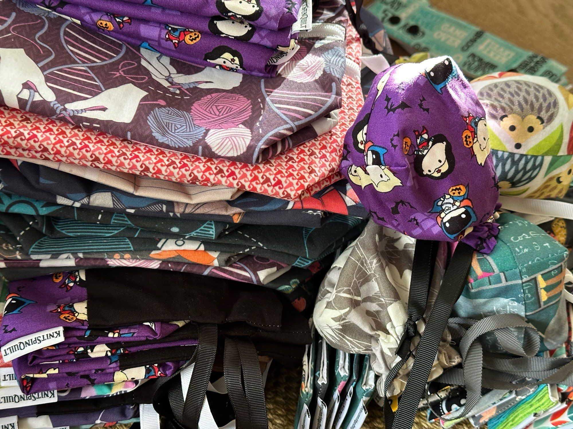 A pile of assorted sizes of fabric drawstring bags ranging from small dice bags to folded larger bags and even some flattened zippered box bags.