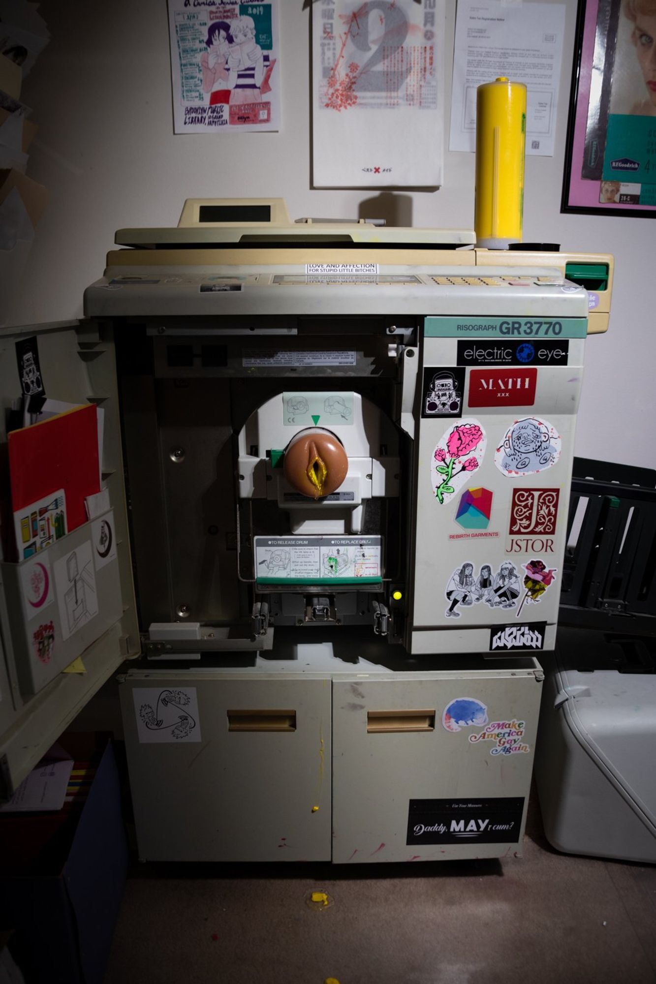 Photo of the Risograph printer with a flashlight in the ink chamber, dripping yellow ink