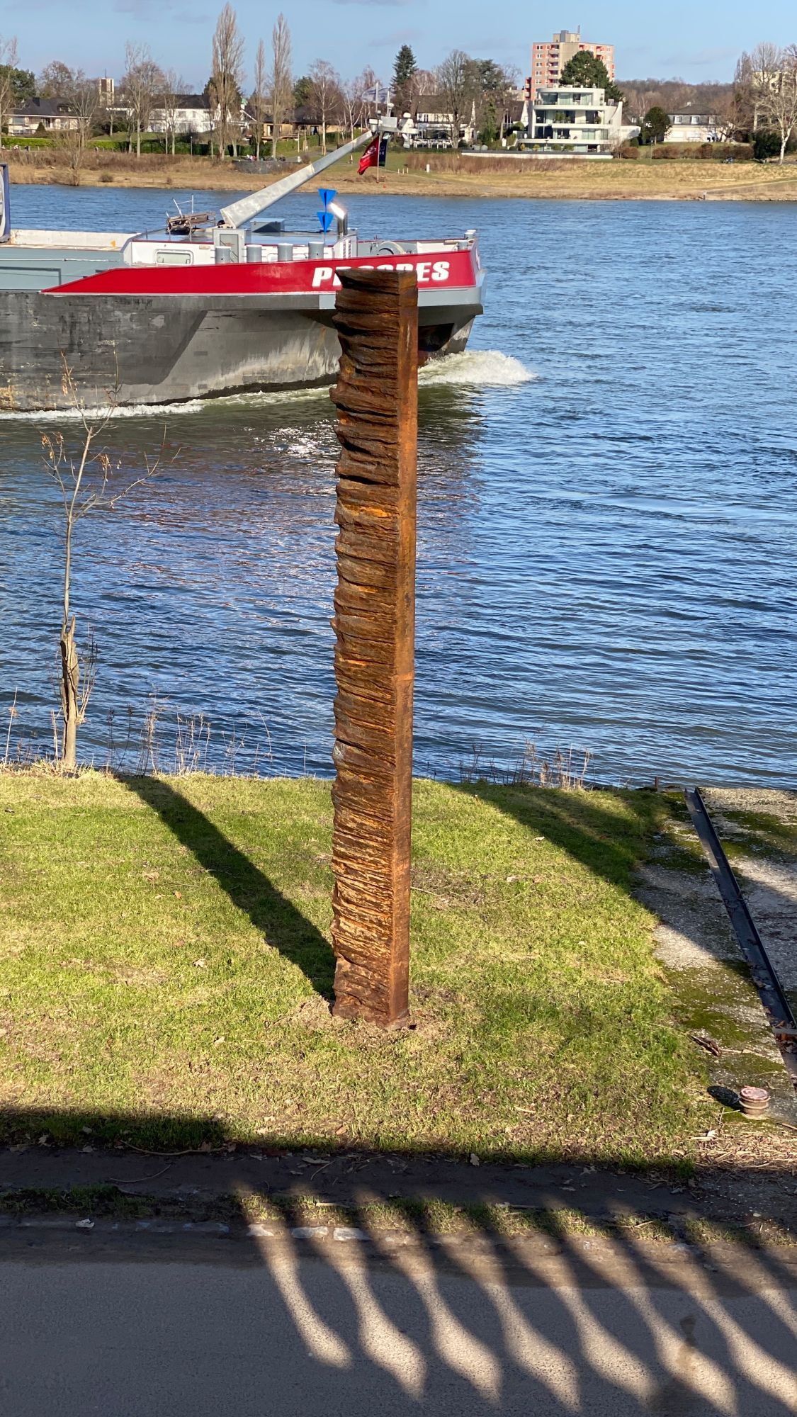 Image of a ship passing by on a river, name half covered.